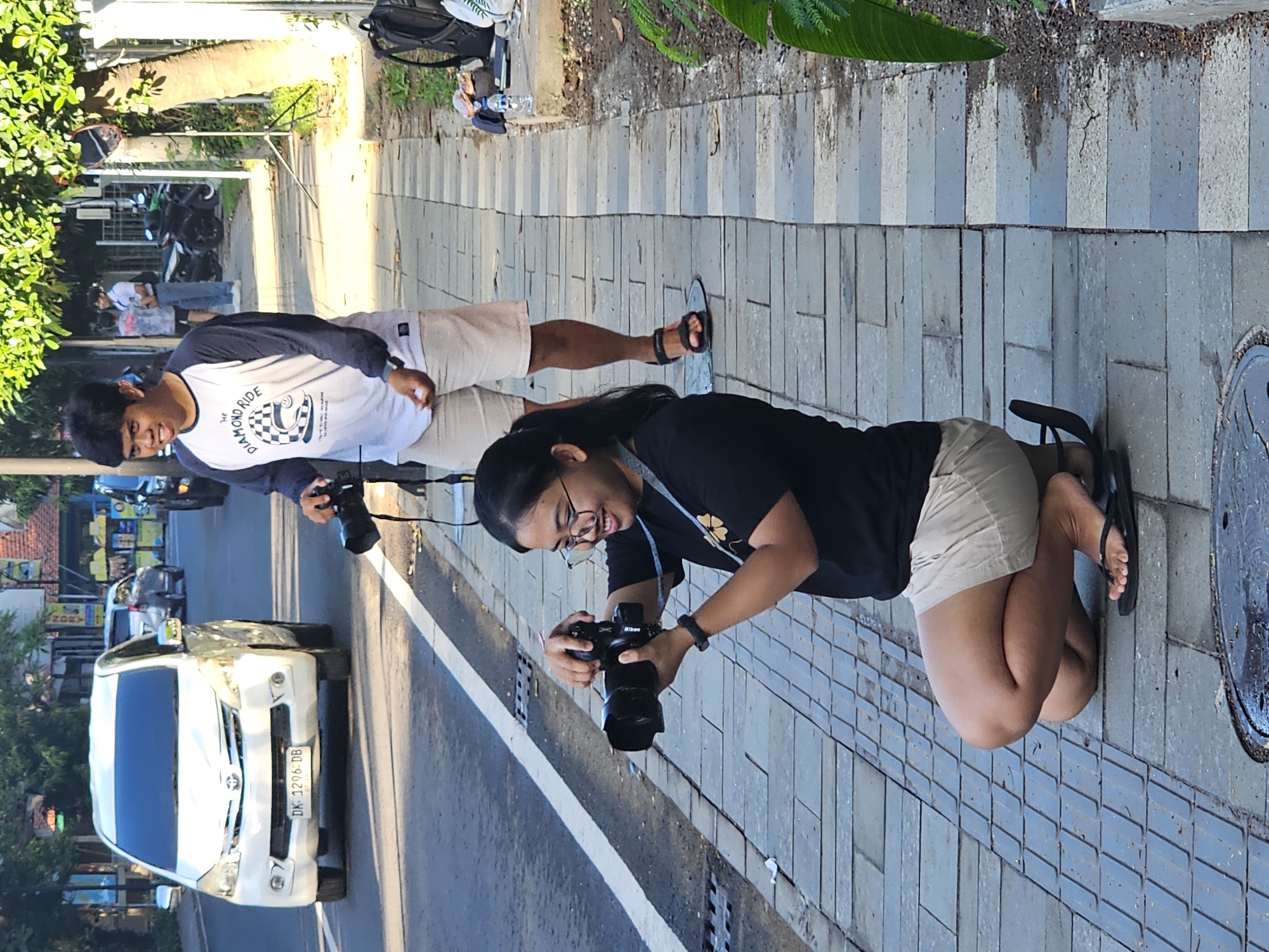 Two people photographing on Denpasar sidewalk at night