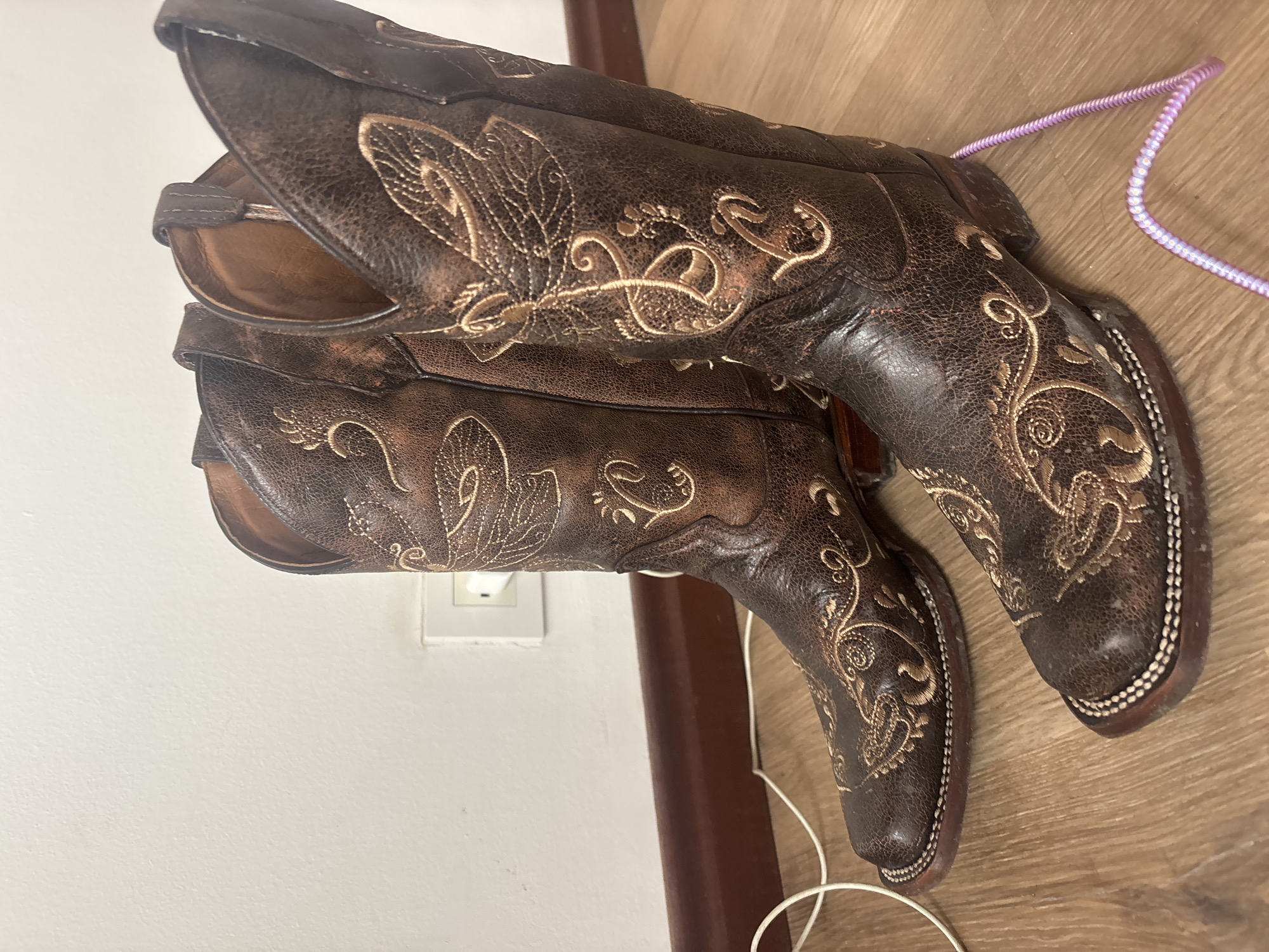 Embroidered cowboy boots spotted on wooden floor in Medellín
