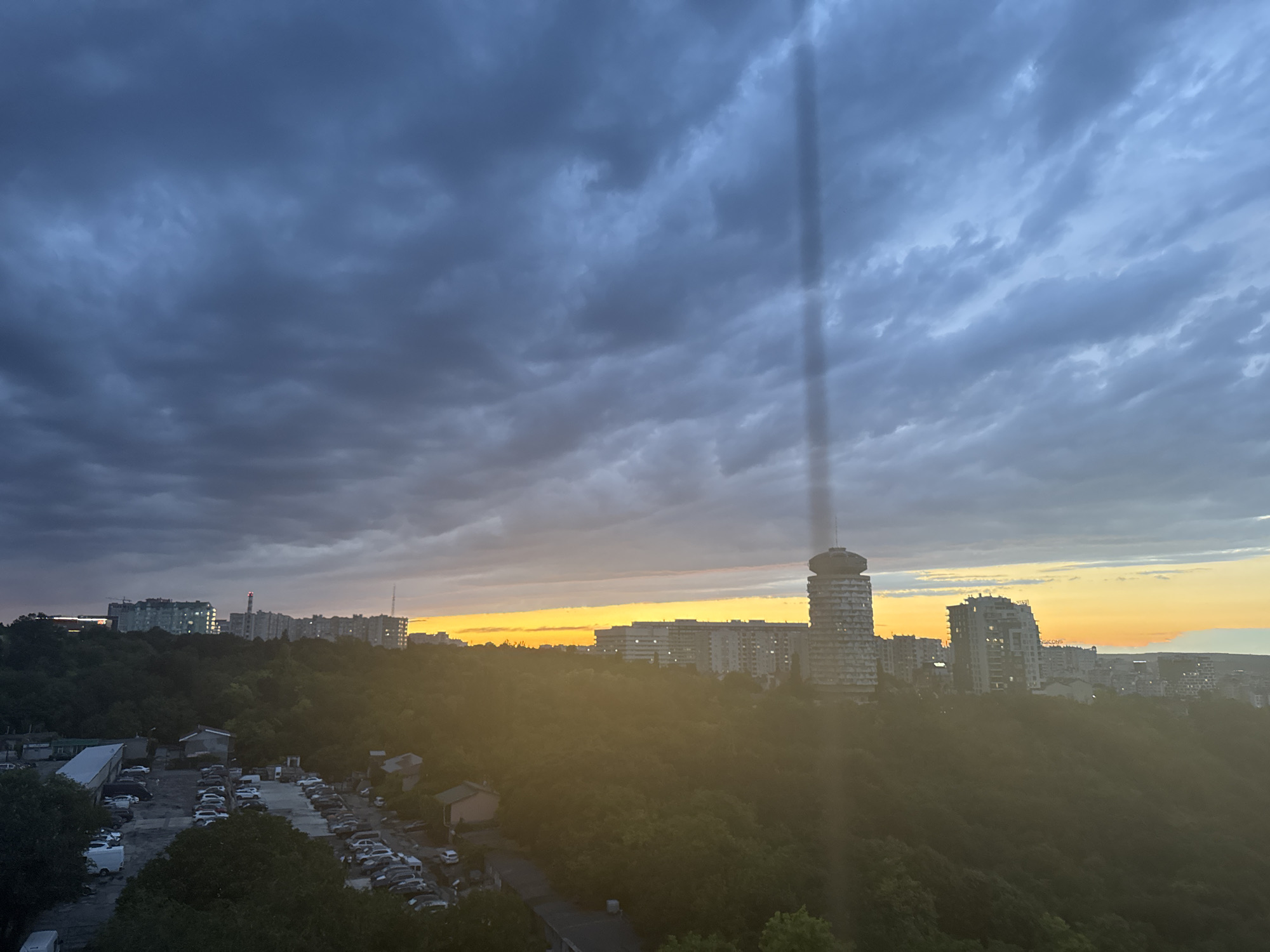 City skyline glows under heavy clouds at golden hour