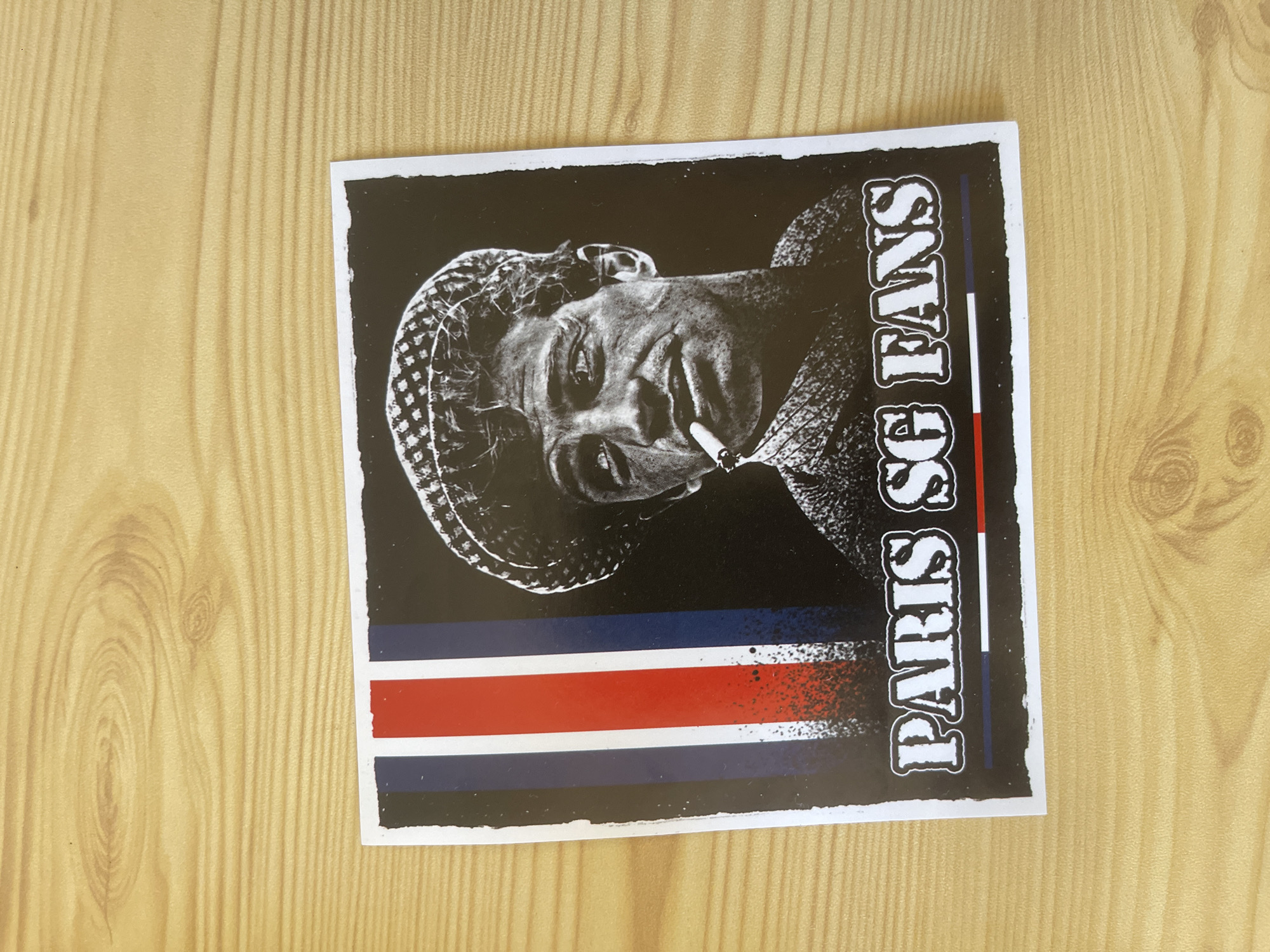 Stickers and a coaster on a wooden surface in Paris