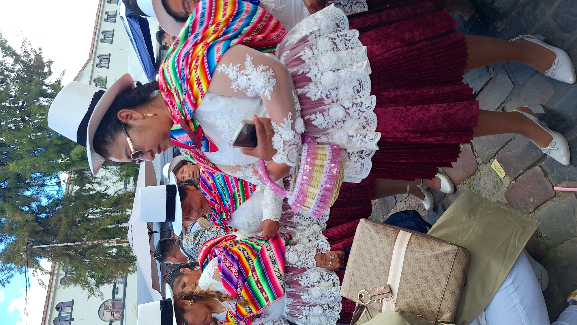 Women in traditional dress gather outdoors in daytime gathering
