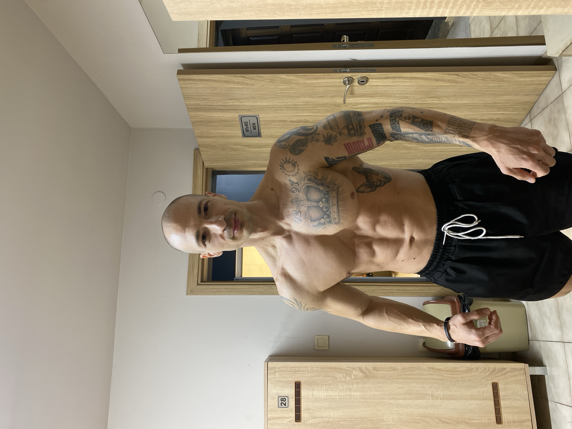 Tattooed man poses shirtless in Pleven locker room