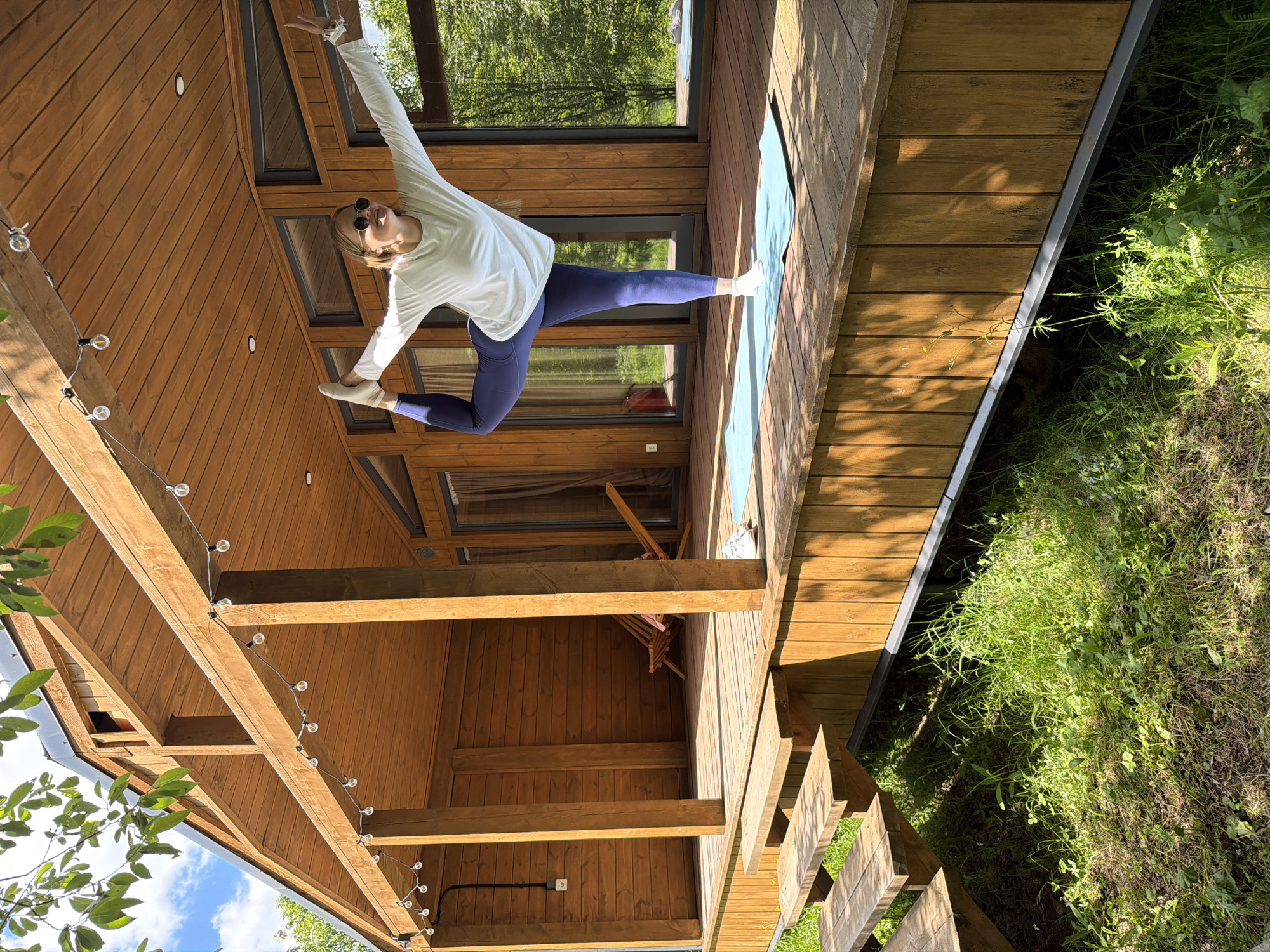 Woman performs morning yoga routine on cabin deck in Russia