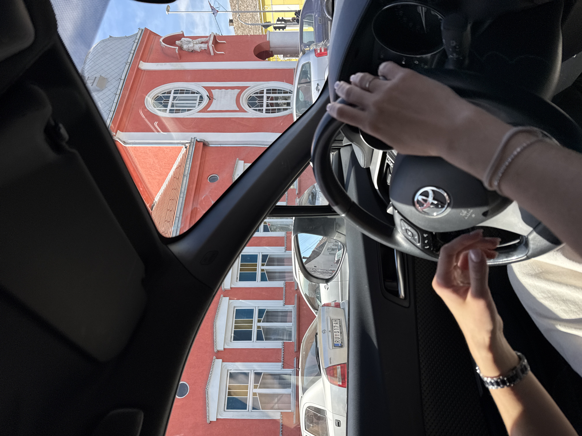 Driver navigates through Ruma Municipality, red building visible