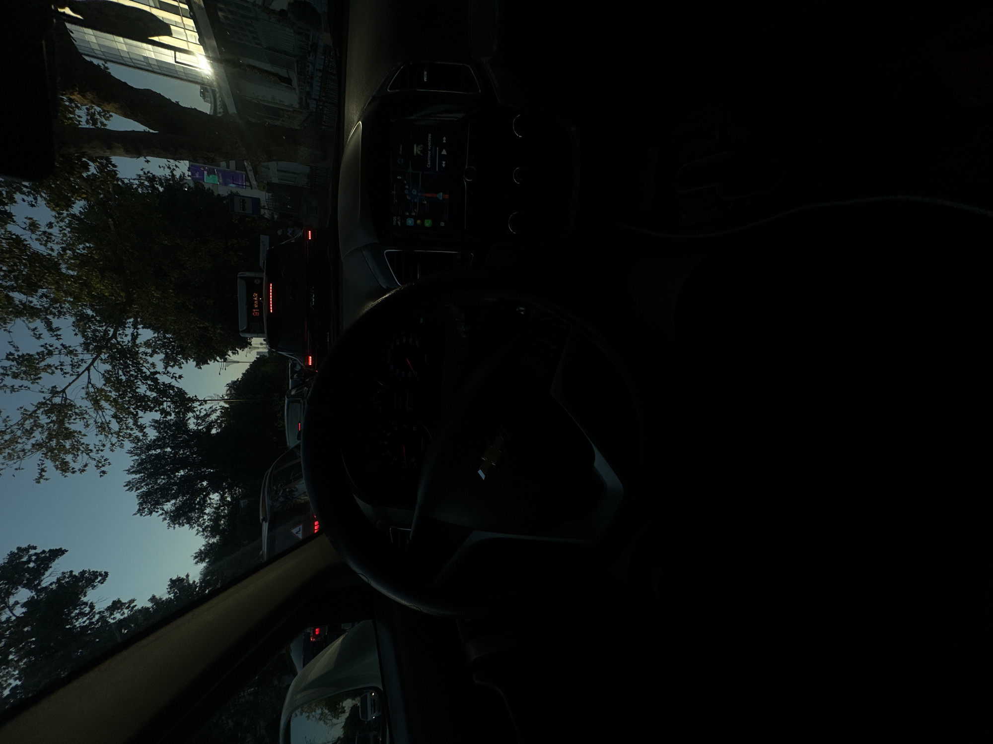 Sitting in Tashkent traffic at dusk, tree-lined street ahead