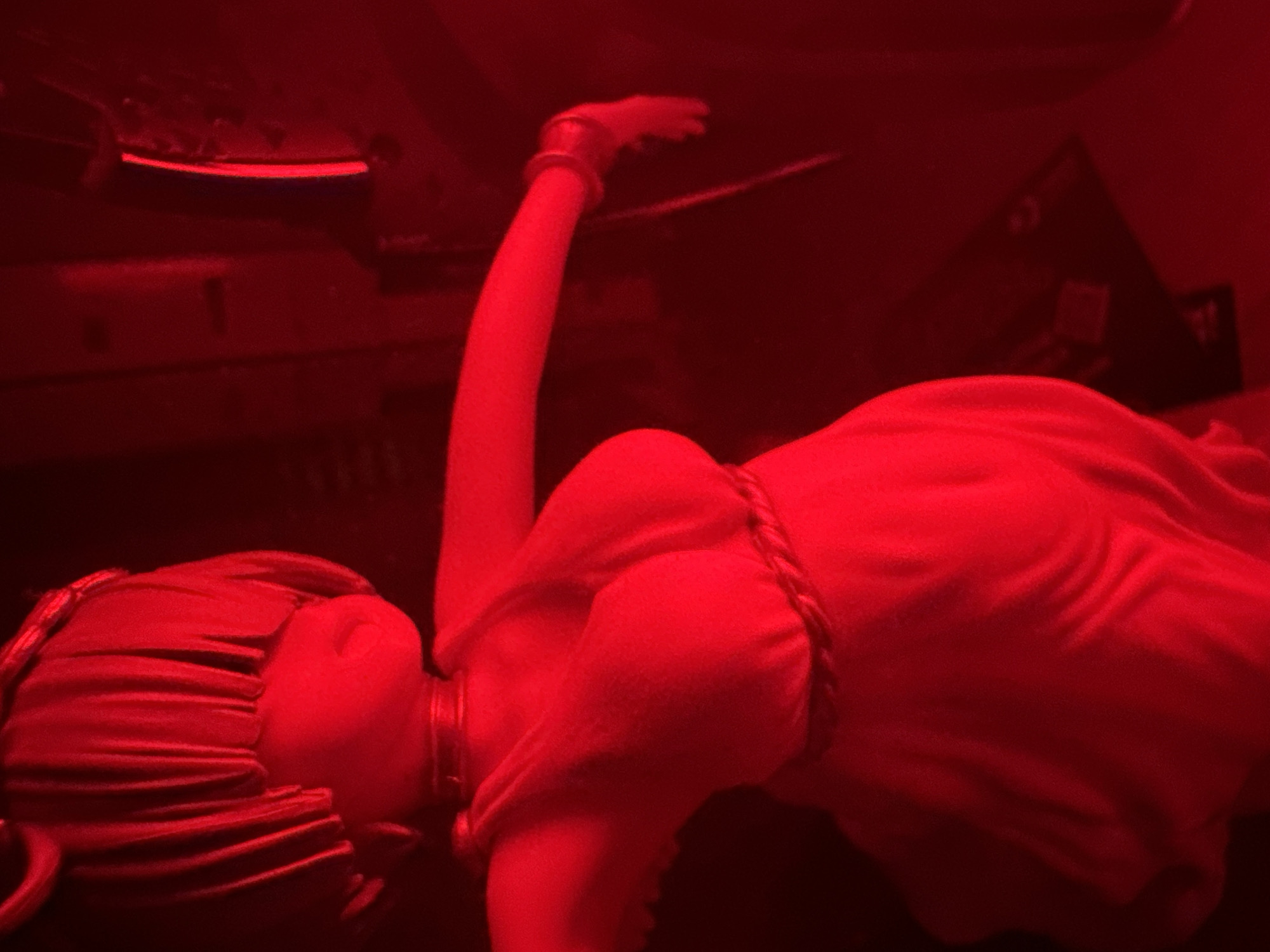 Red-lit anime figurine photography session with winged characters