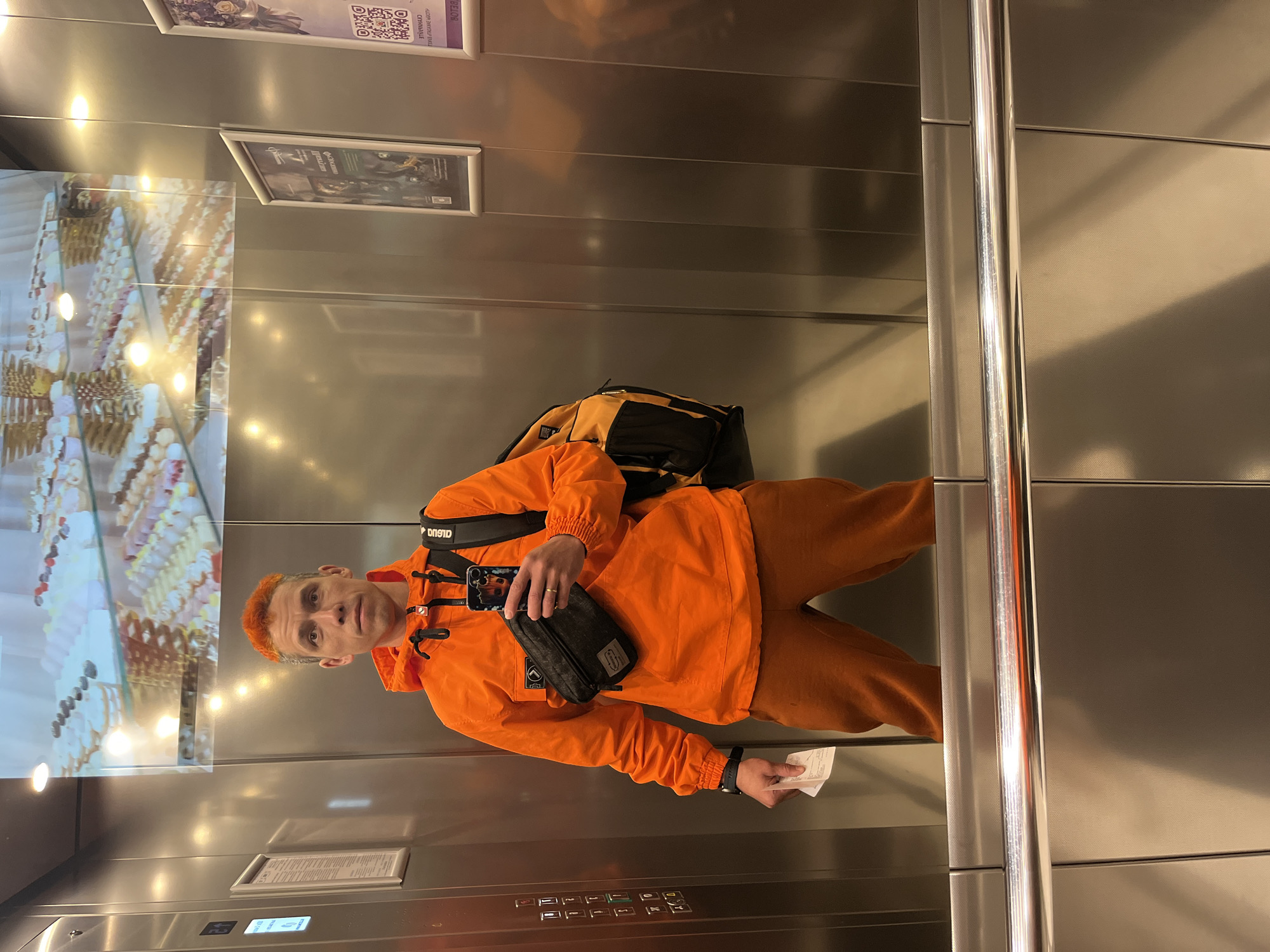 Orange-clad man with phone, ticket observed in Moscow elevator