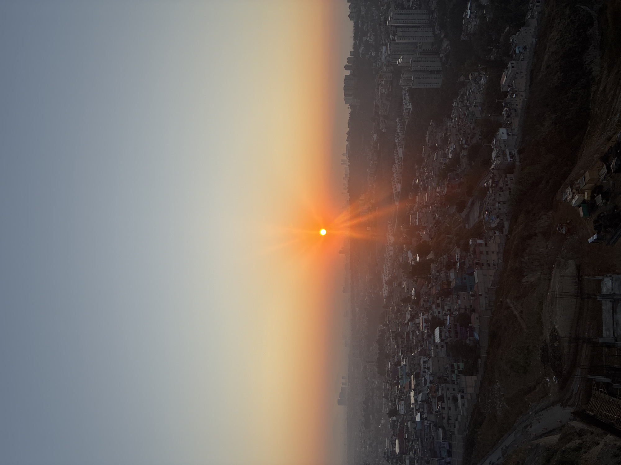 Hazy orange sunset illuminates Huixquilucan de Degollado cityscape