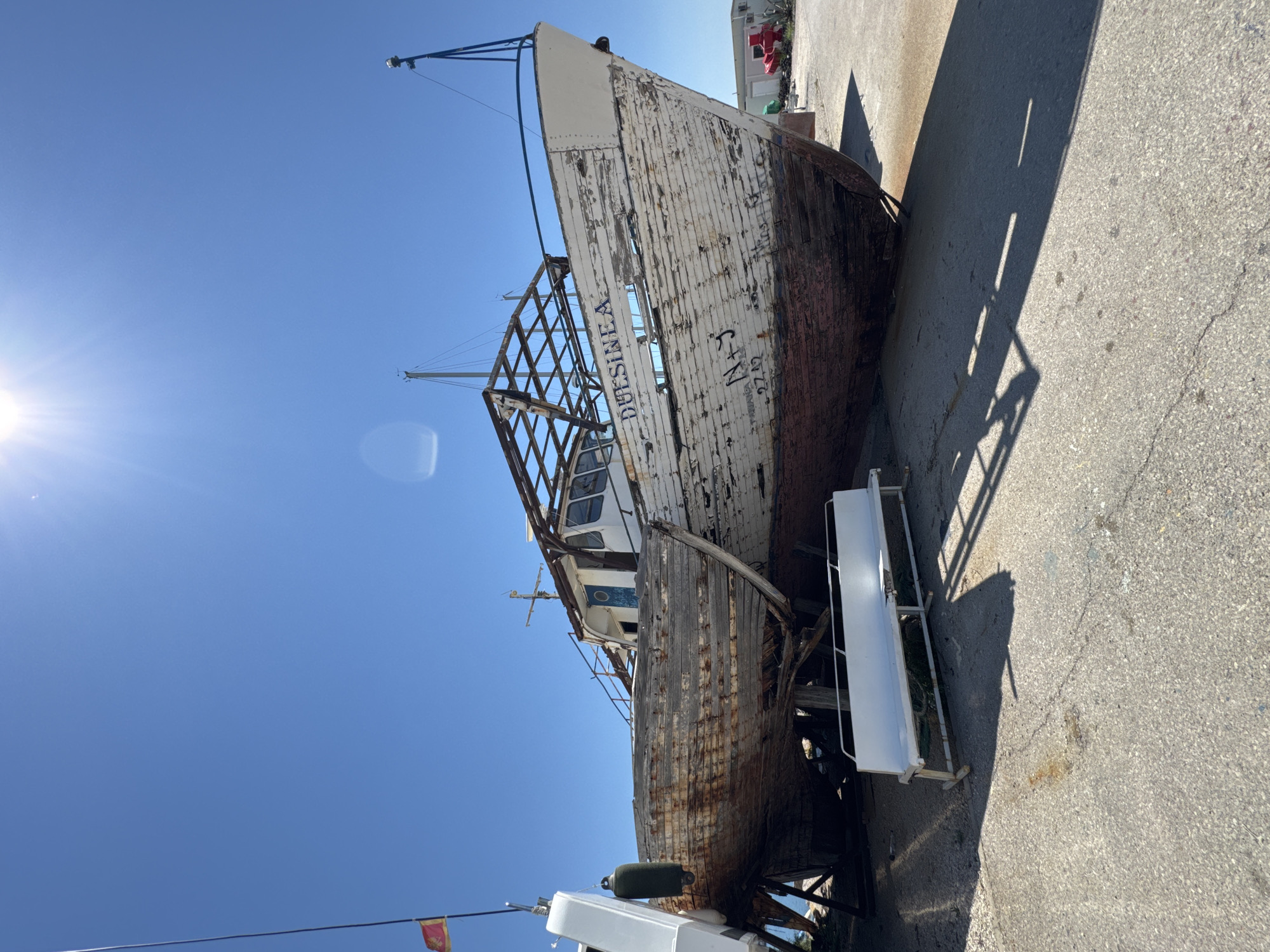 Weathered wooden boat mid-restoration on dry land in Bar