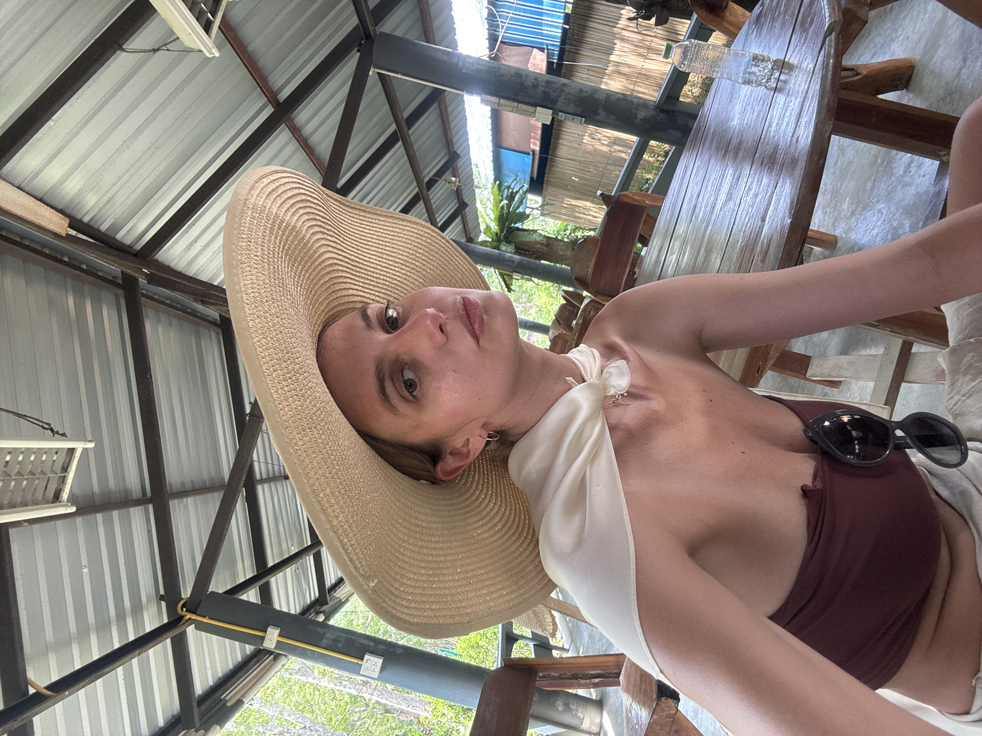 Woman in straw hat photographed at wooden surface