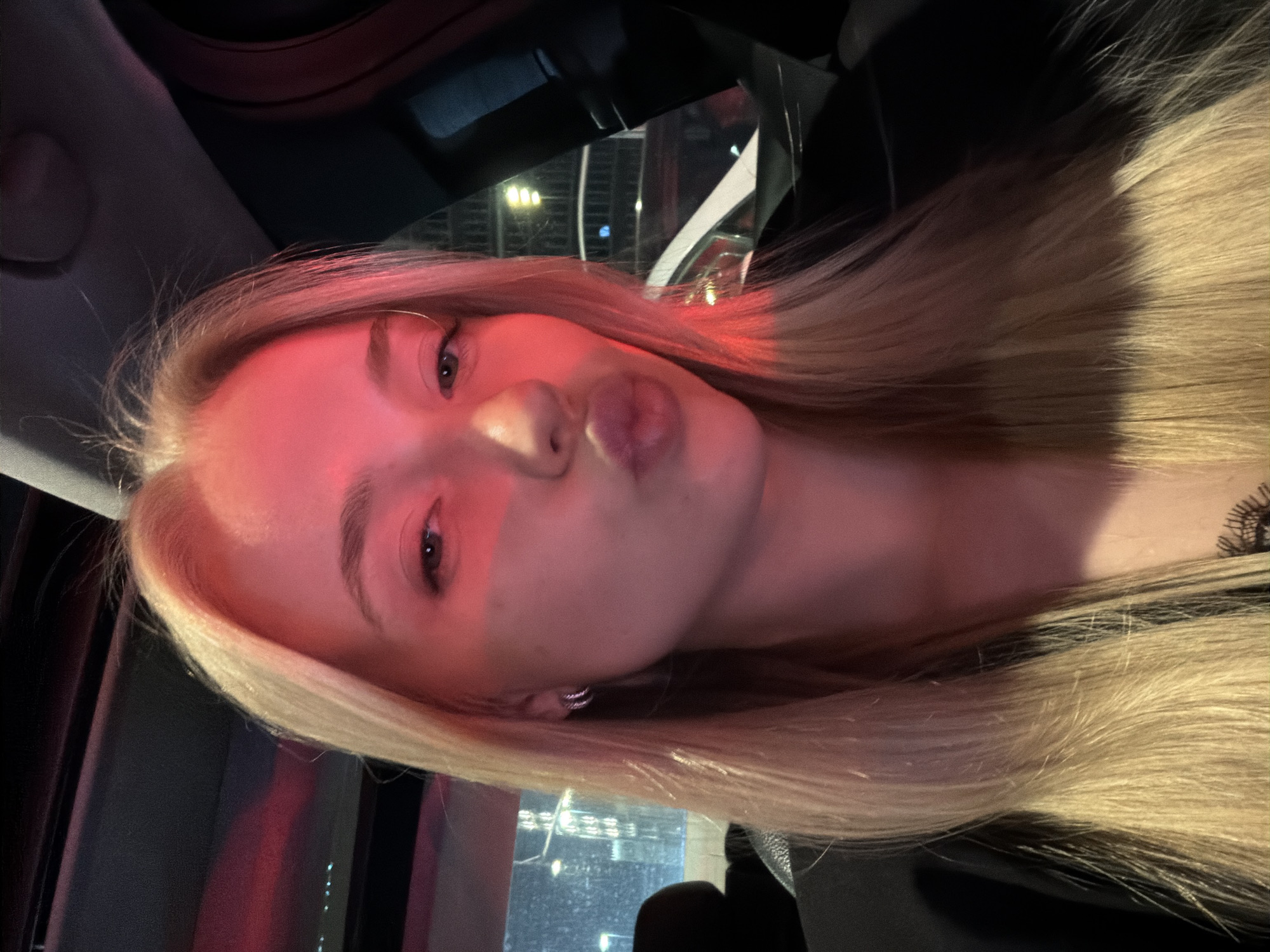 Woman Takes Nighttime Car Selfies With City Lights Backdrop