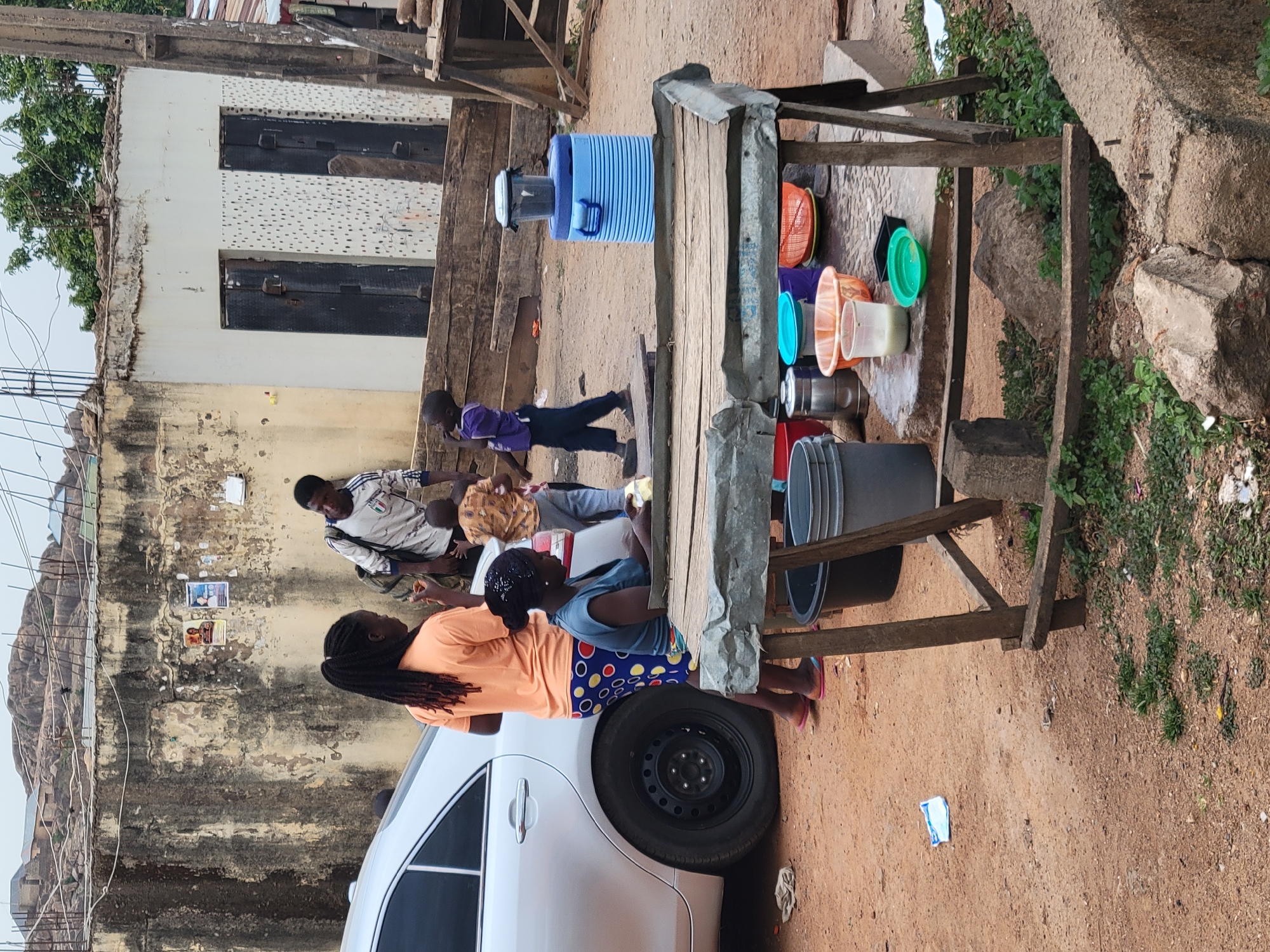Daily life unfolds around water stand, children play in Jos streets