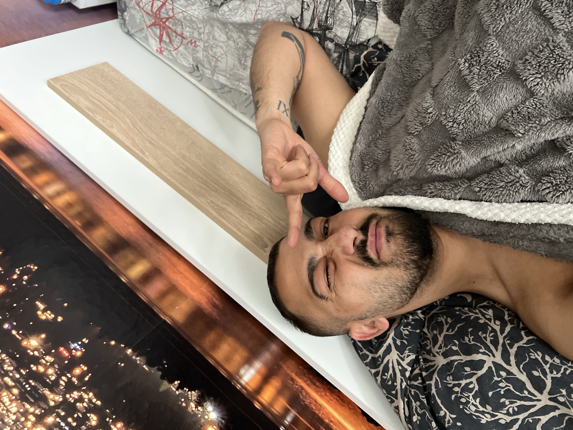 Man rests under blankets near framed artwork in Shumata