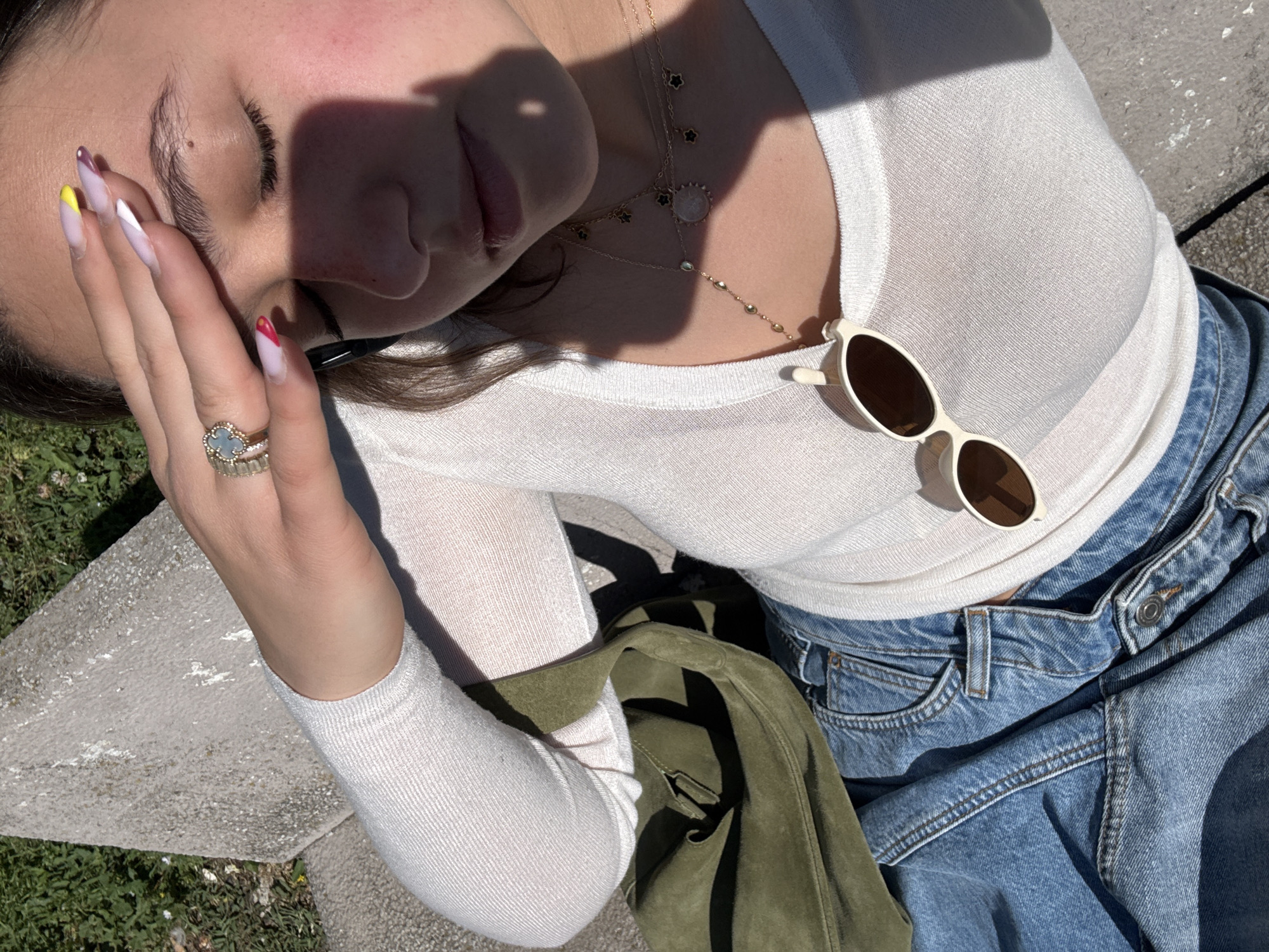 Woman rests in Milan park wearing denim and jewelry