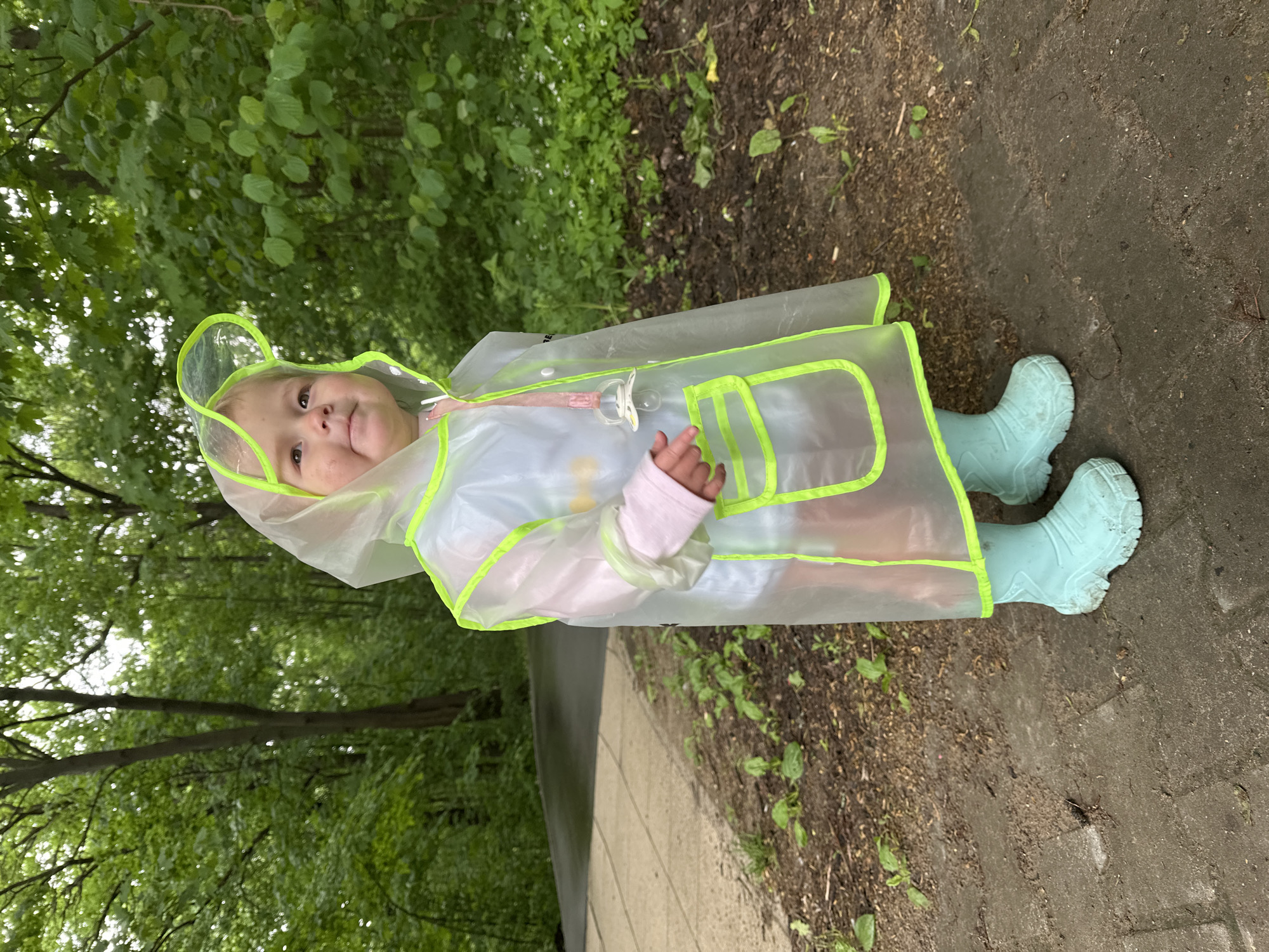 Child in frog raincoat plays in puddles at Nizhny Novgorod park
