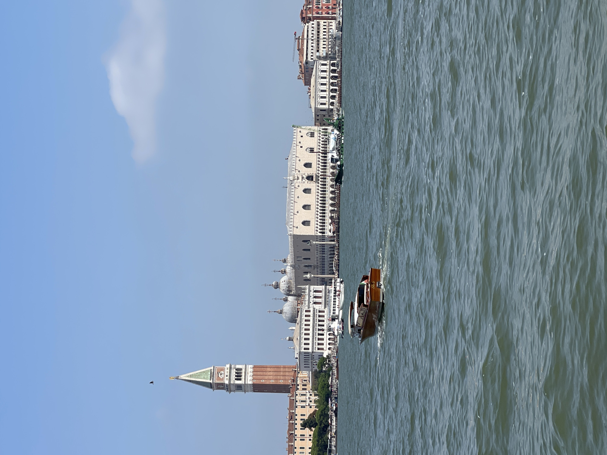 Boat cuts through choppy urban waterway with city skyline visible