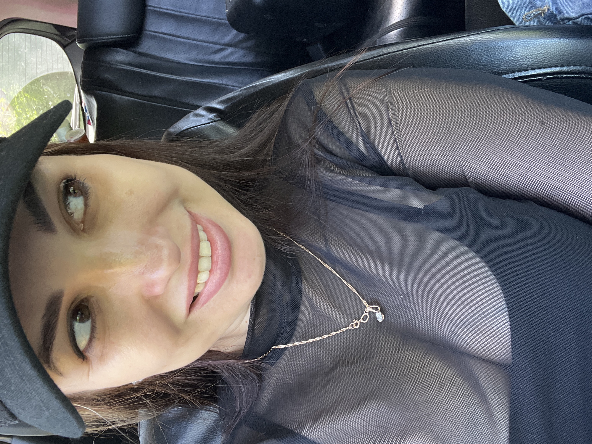 Woman photographed in car wearing black outfit and cap