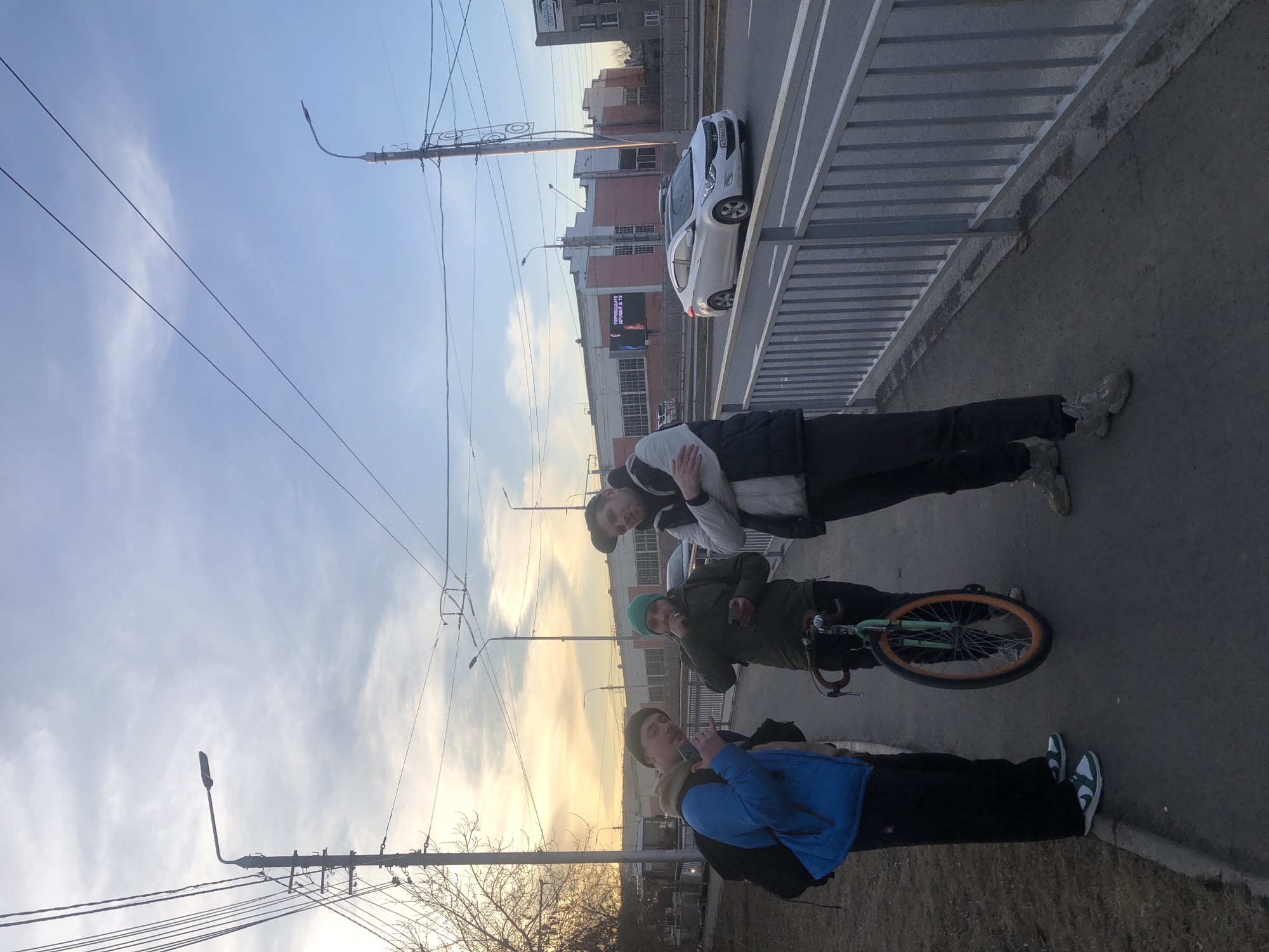 Three men gather on Krasnoyarsk sidewalk during evening hours
