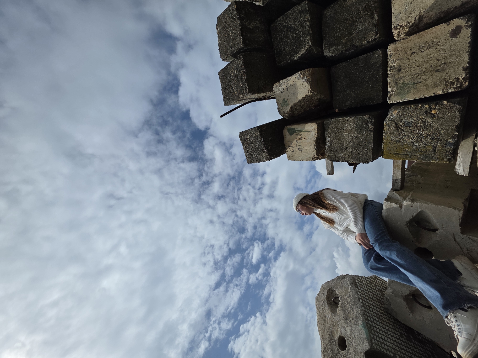 Person sits on concrete blocks in casual outfit