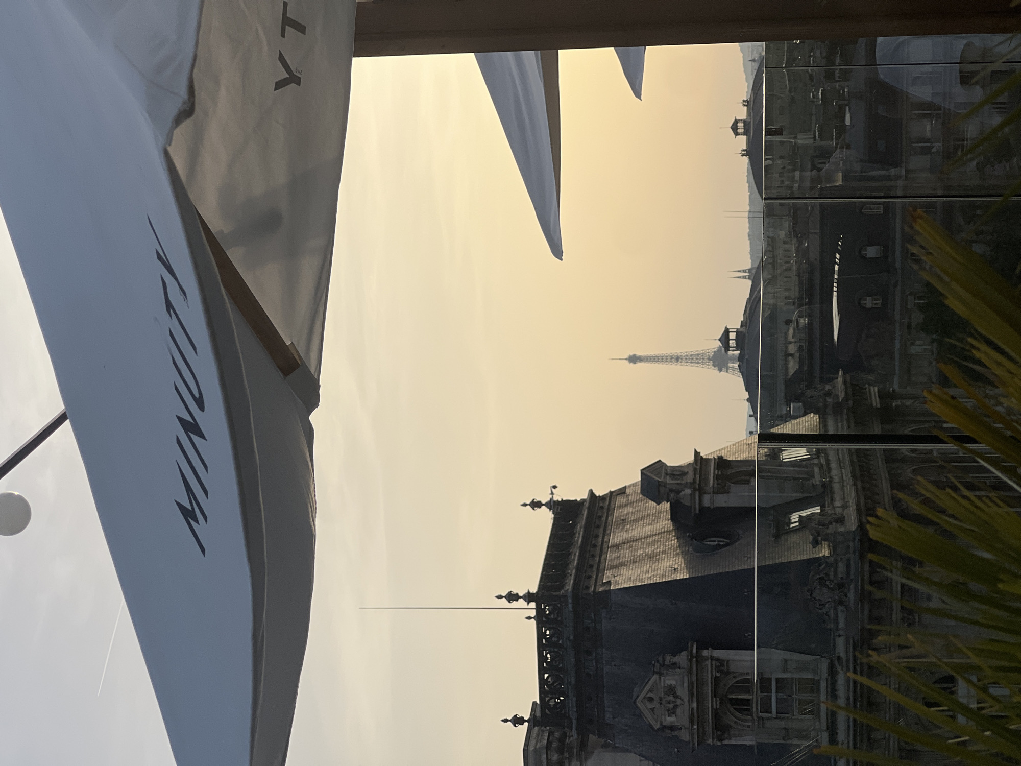 Rooftop view captures Eiffel Tower through hazy Paris evening