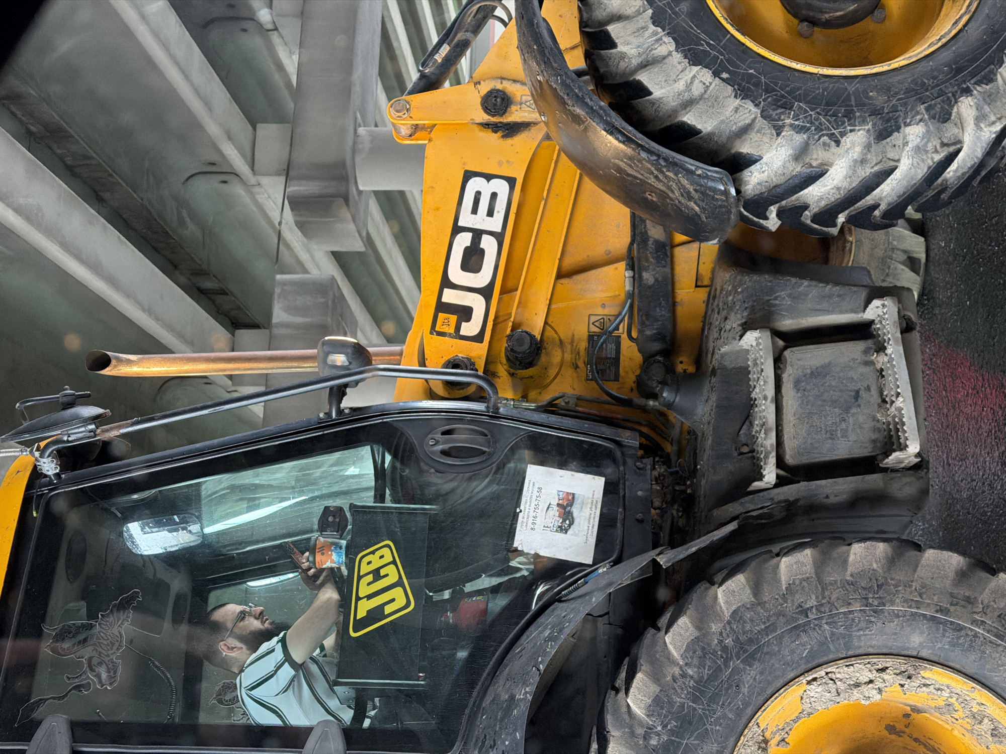 Construction worker operates backhoe while holding unidentified object