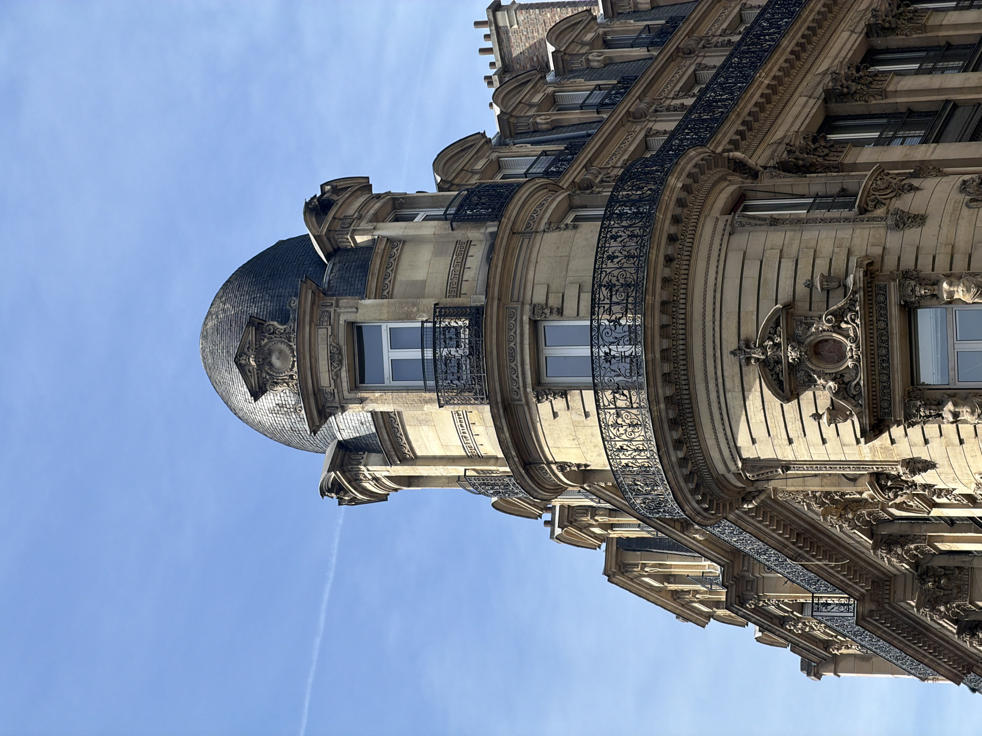 Tourist photographs classic Parisian building architecture under clear skies