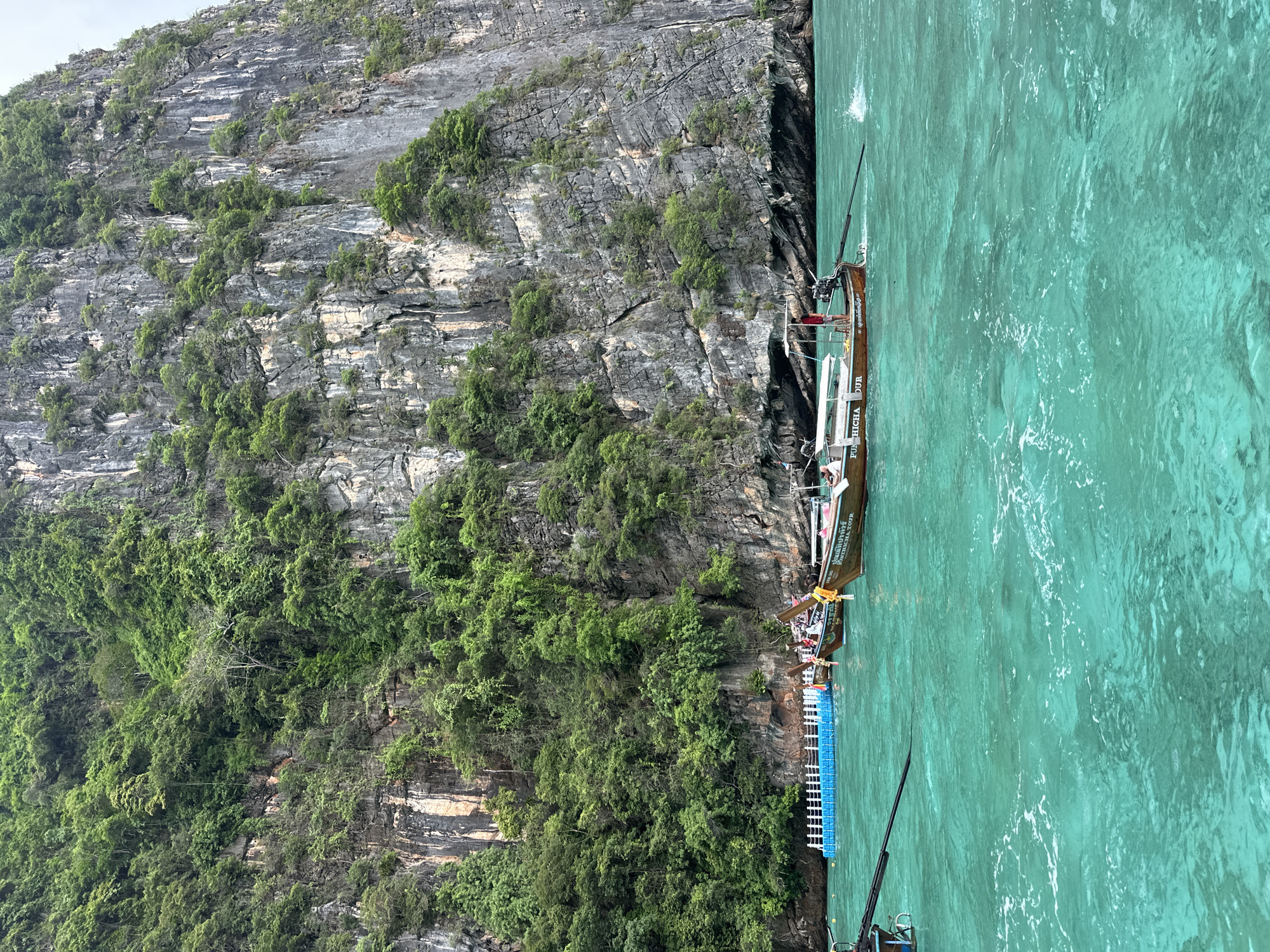 Speedboat and longtail boats navigate Haad Yao's limestone coastline