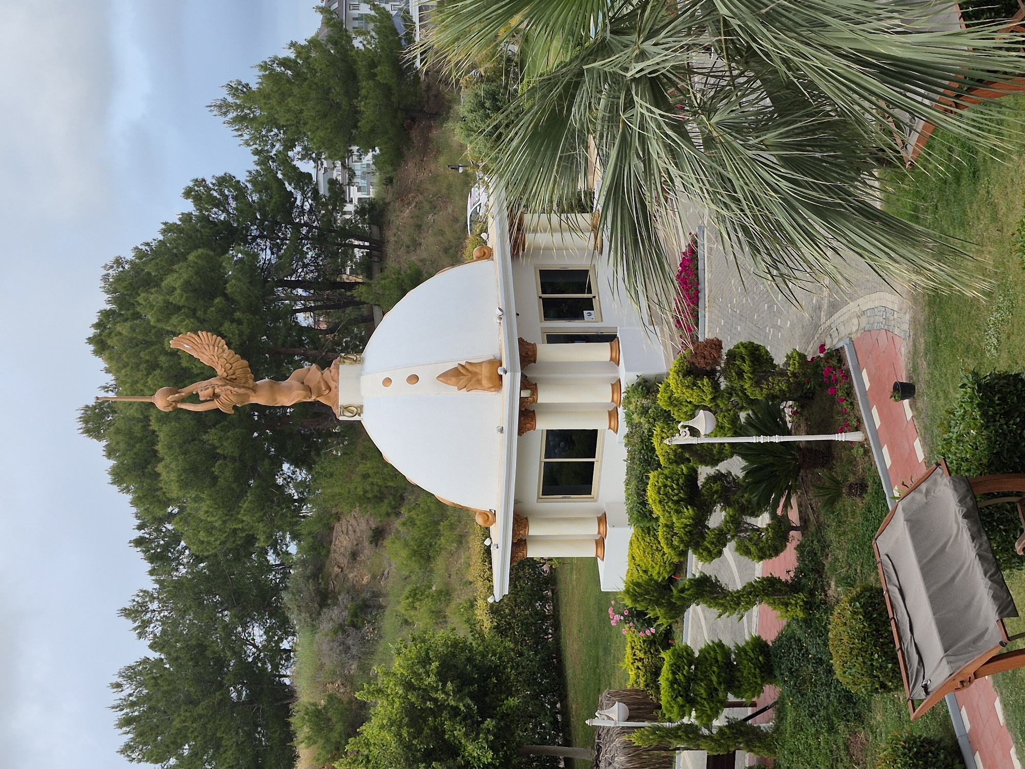 Building with golden winged statue, garden documented in Alanya
