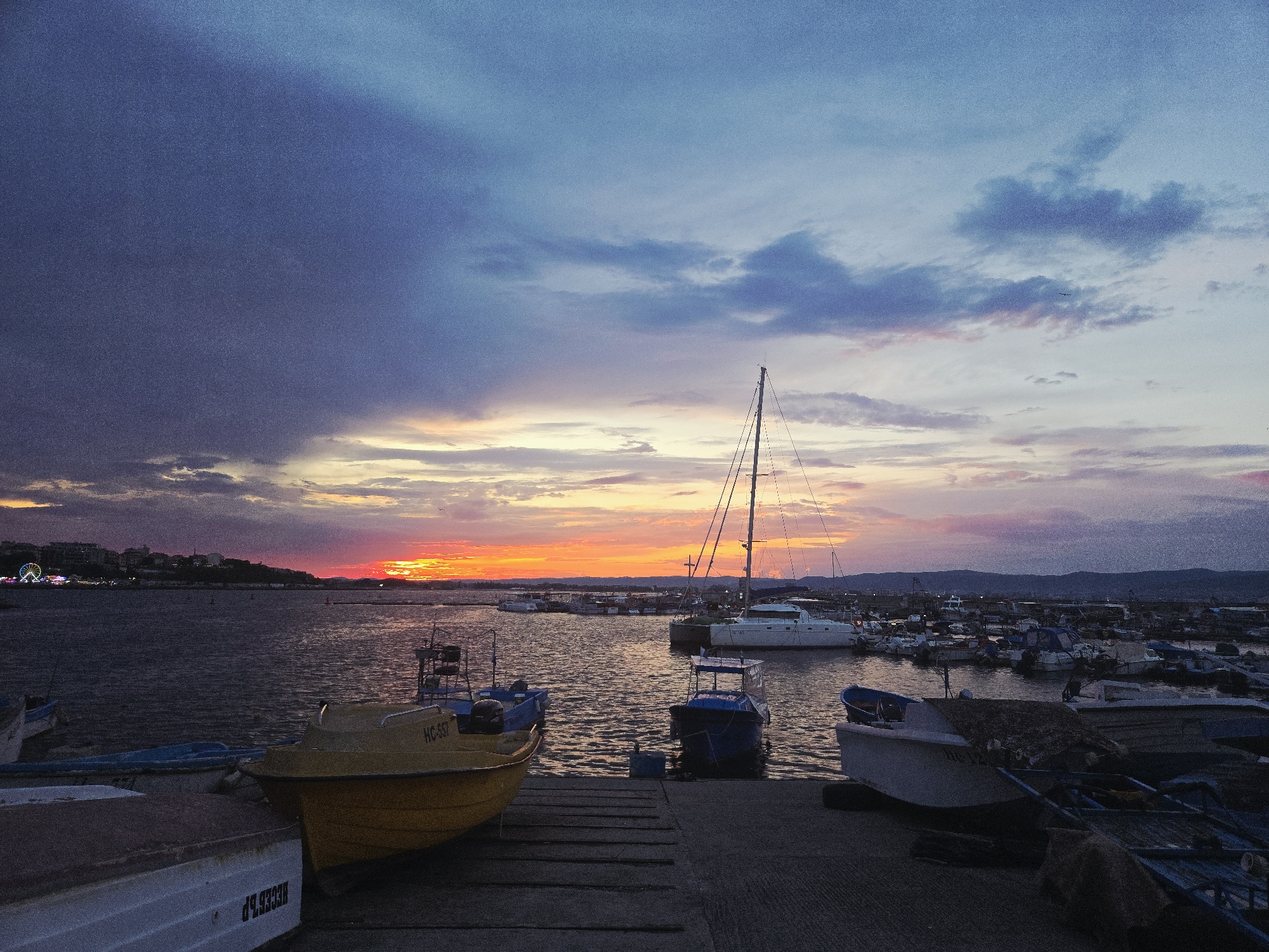Dusk settles over a harbor marina with abstract sculpture