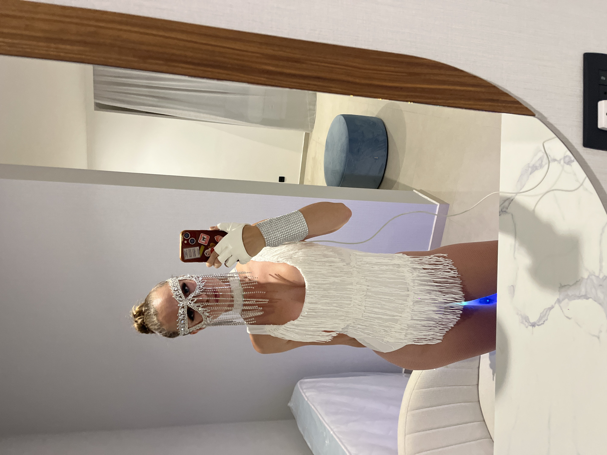 Mirror selfie in rhinestone mask and light-up rainbow cape, Bar