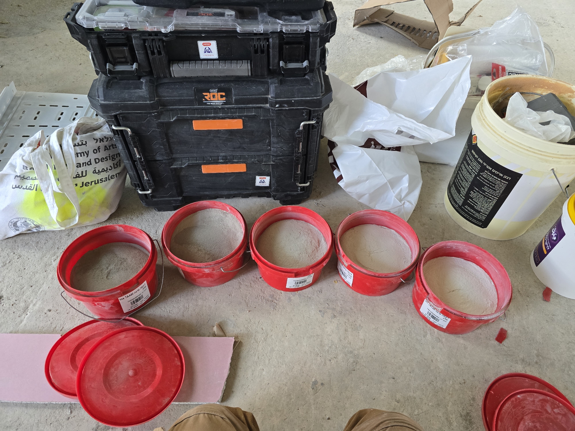 Construction materials and buckets documented on concrete floor