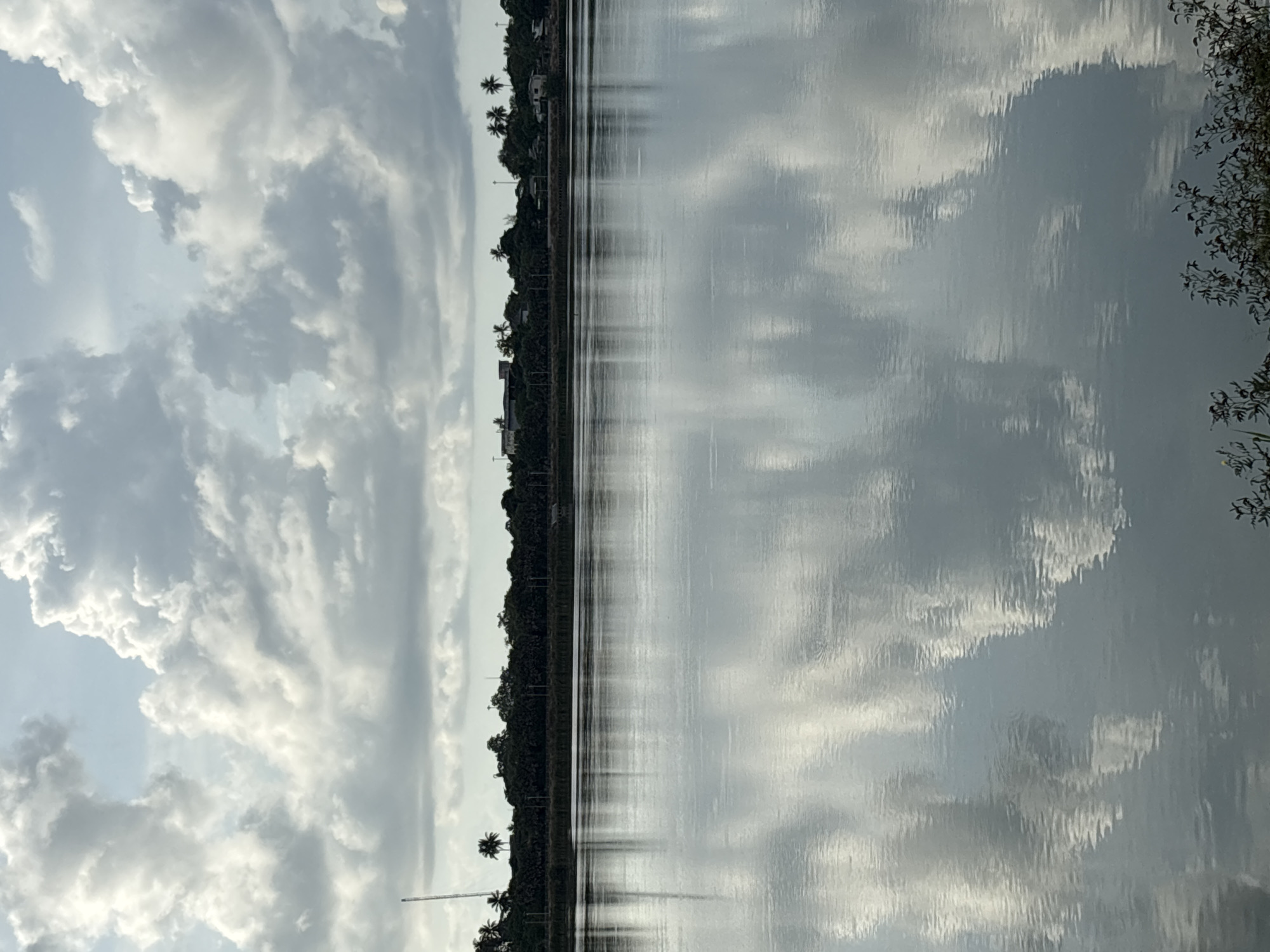 Cloudy sky reflects in Thai waterway near populated area