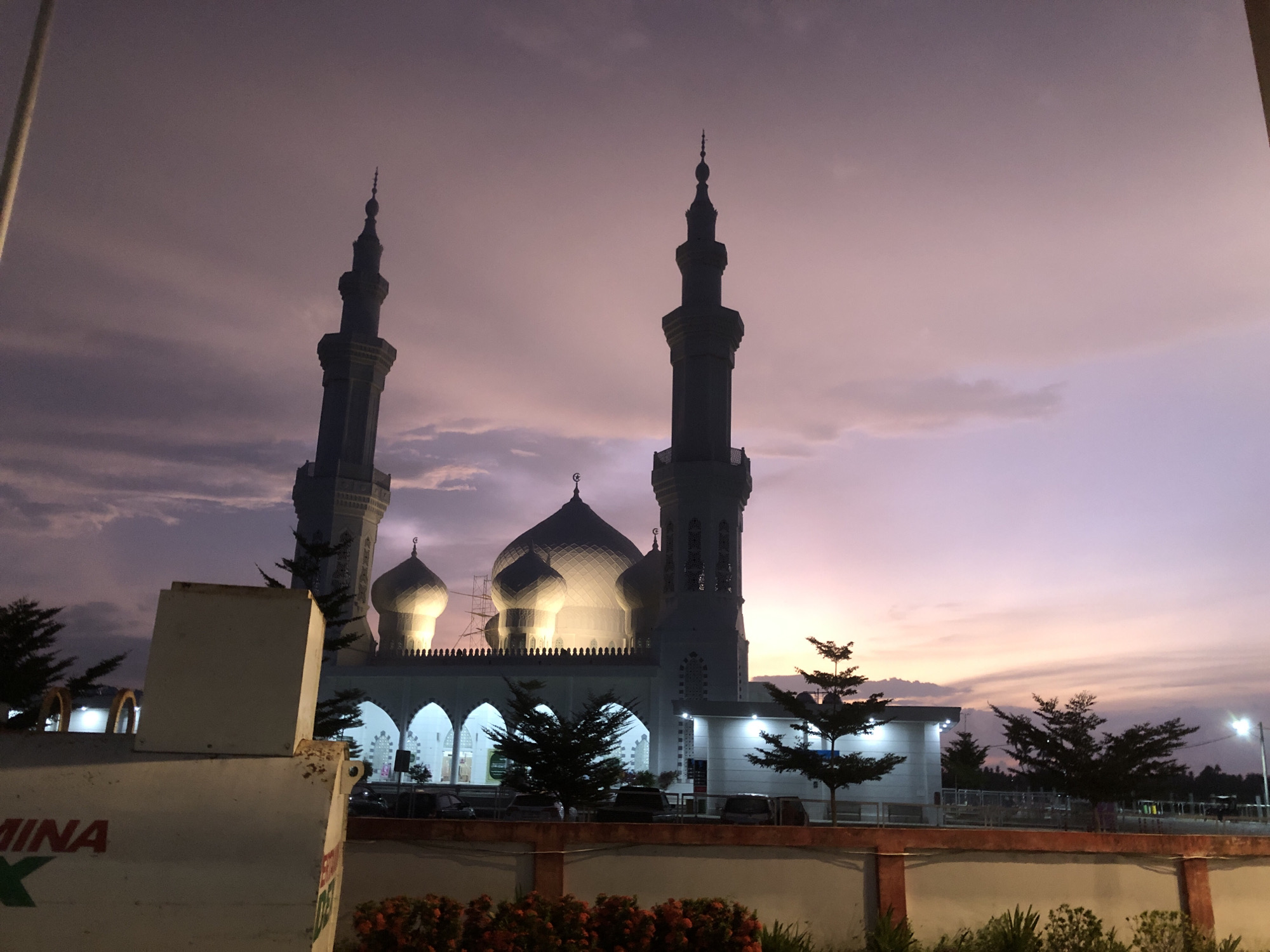 Indonesian mosque glowing at twilight, minarets against a pink sky