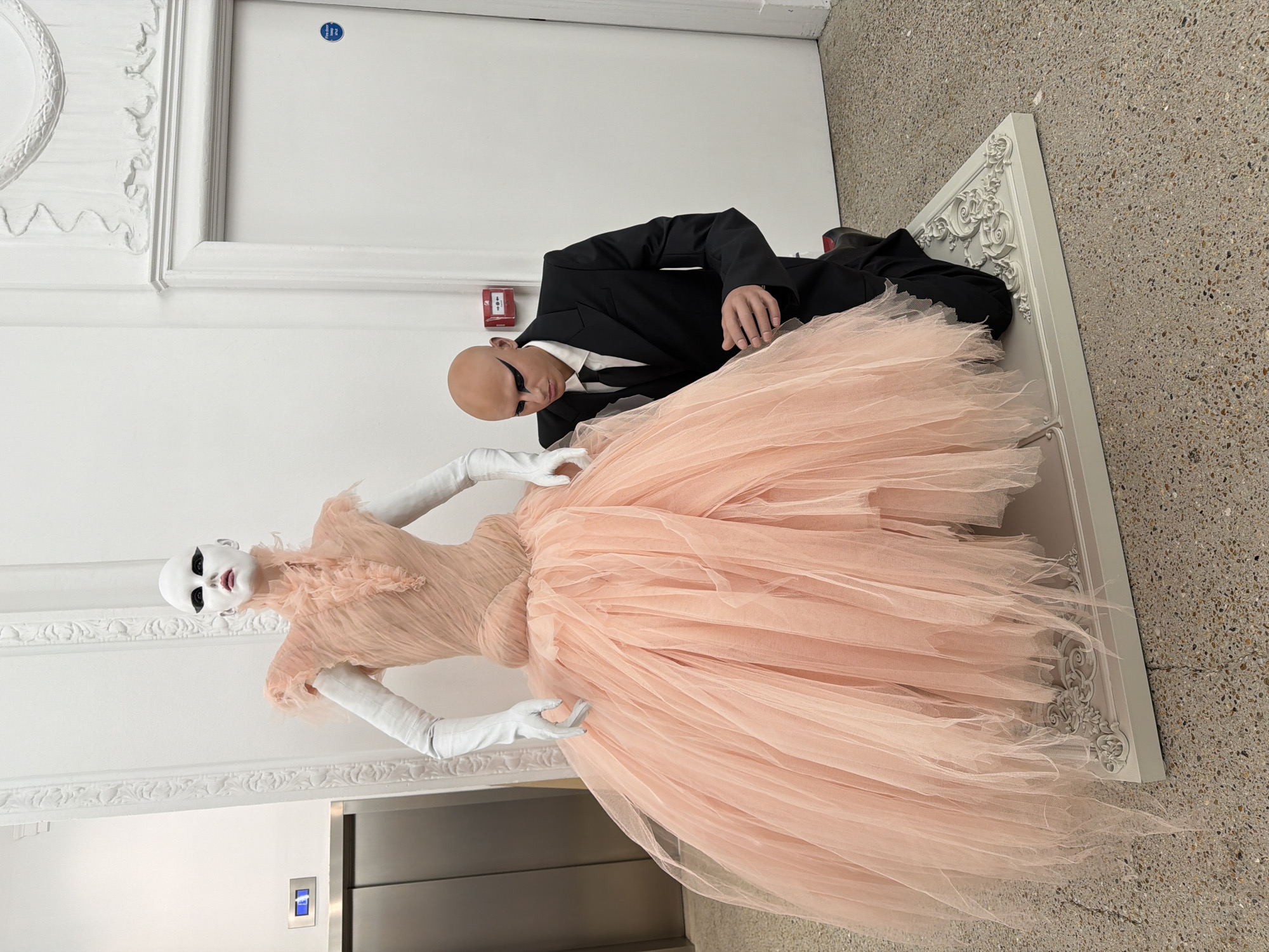 Man adjusts formal mannequin display in London clothing store