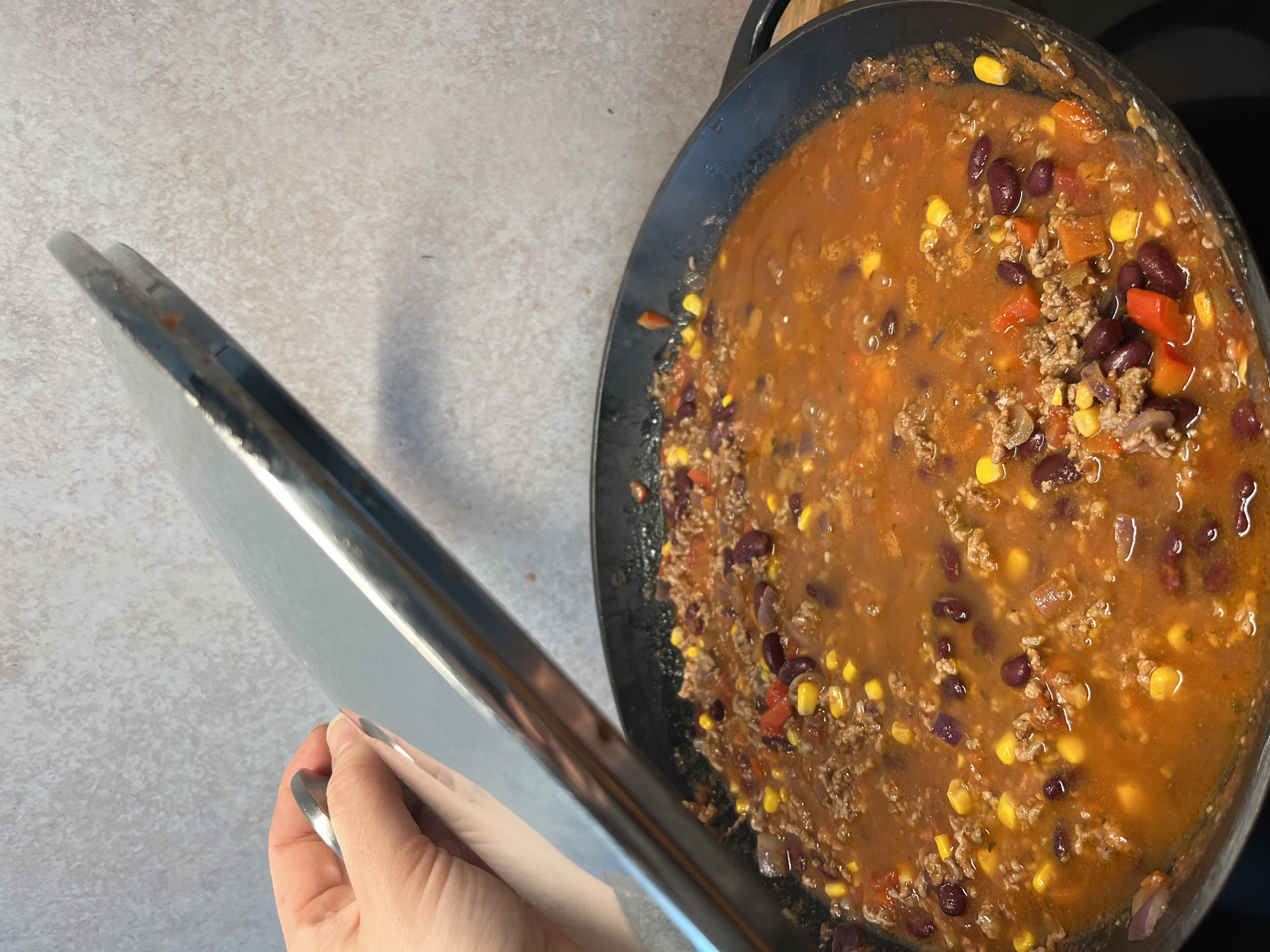 Person prepares chili with beans, corn in German kitchen