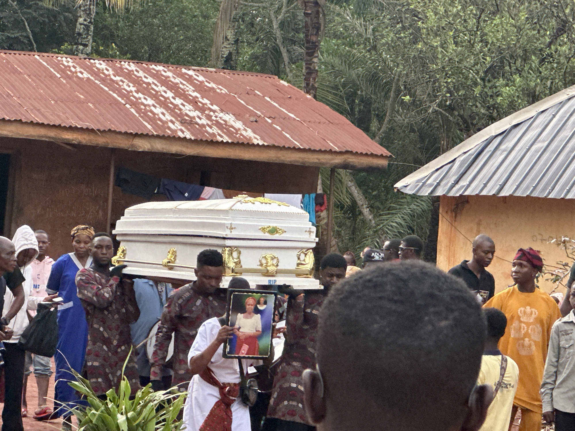 Funeral procession with white coffin observed in rural area