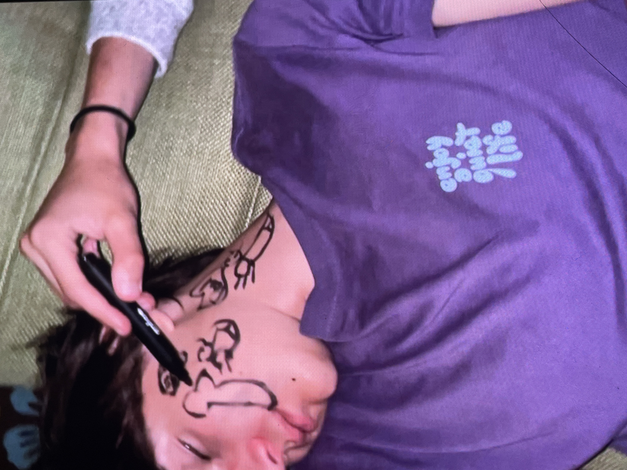 Black marker doodles cover a face during a sofa session