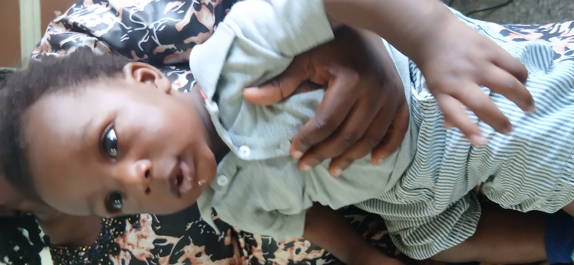 Woman holds baby while man stands in doorway, Shaba Nigeria