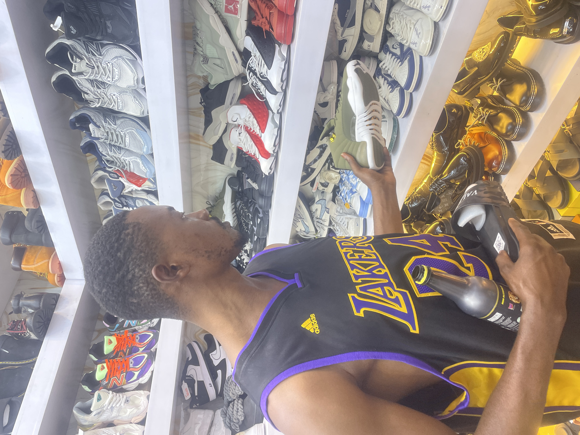 Young men browse shoes while drinking energy drinks in Jos store