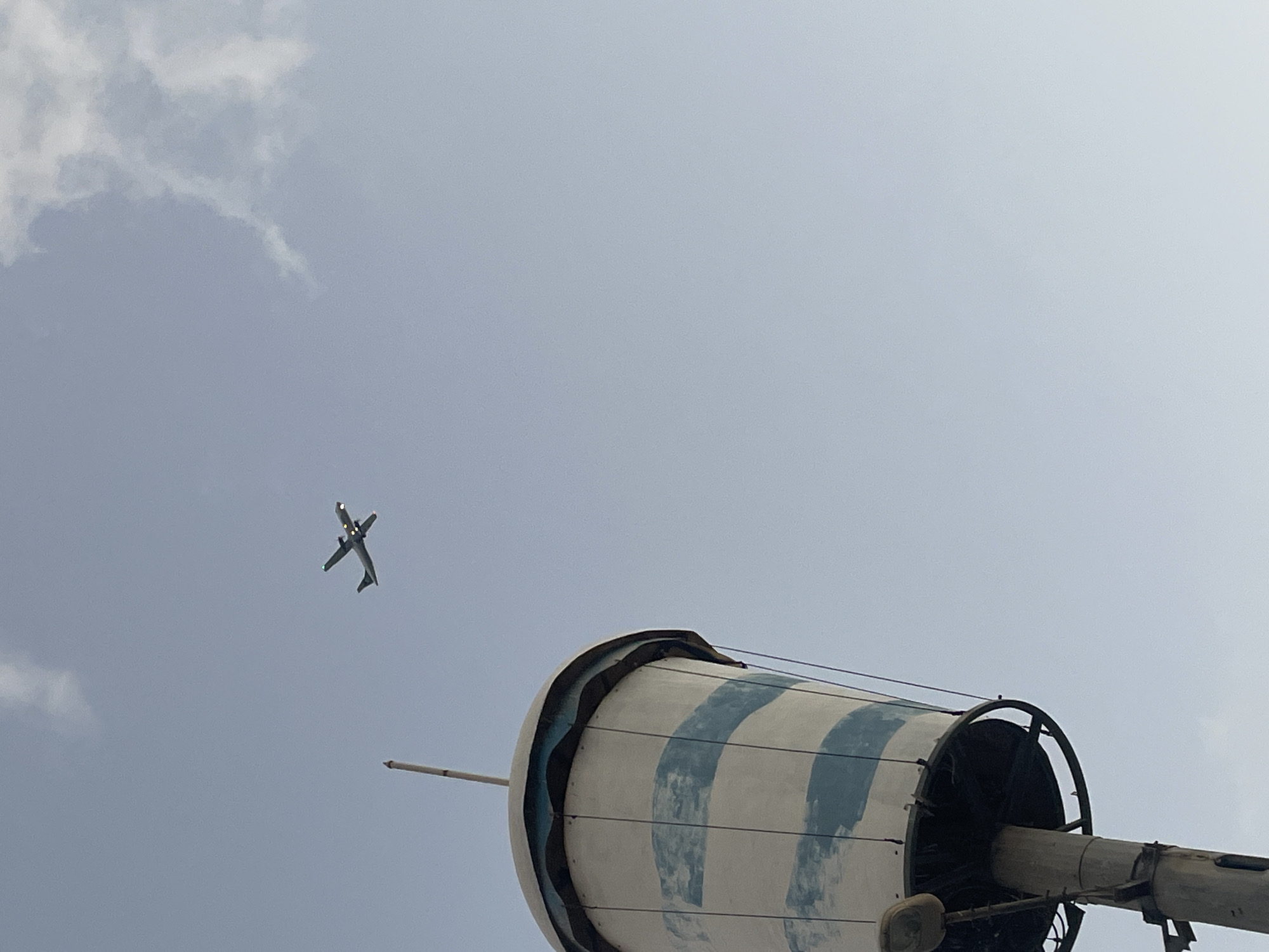 Turboprop crosses cloudy skies over Kiryat Yam's coastal streets at dusk