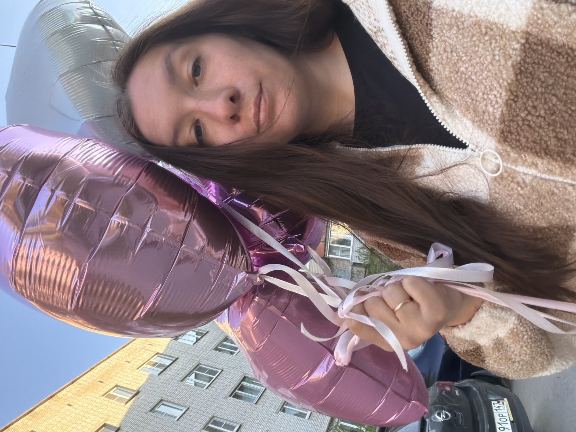 Woman holds heart-shaped balloons in sunny Tokkari, Russia