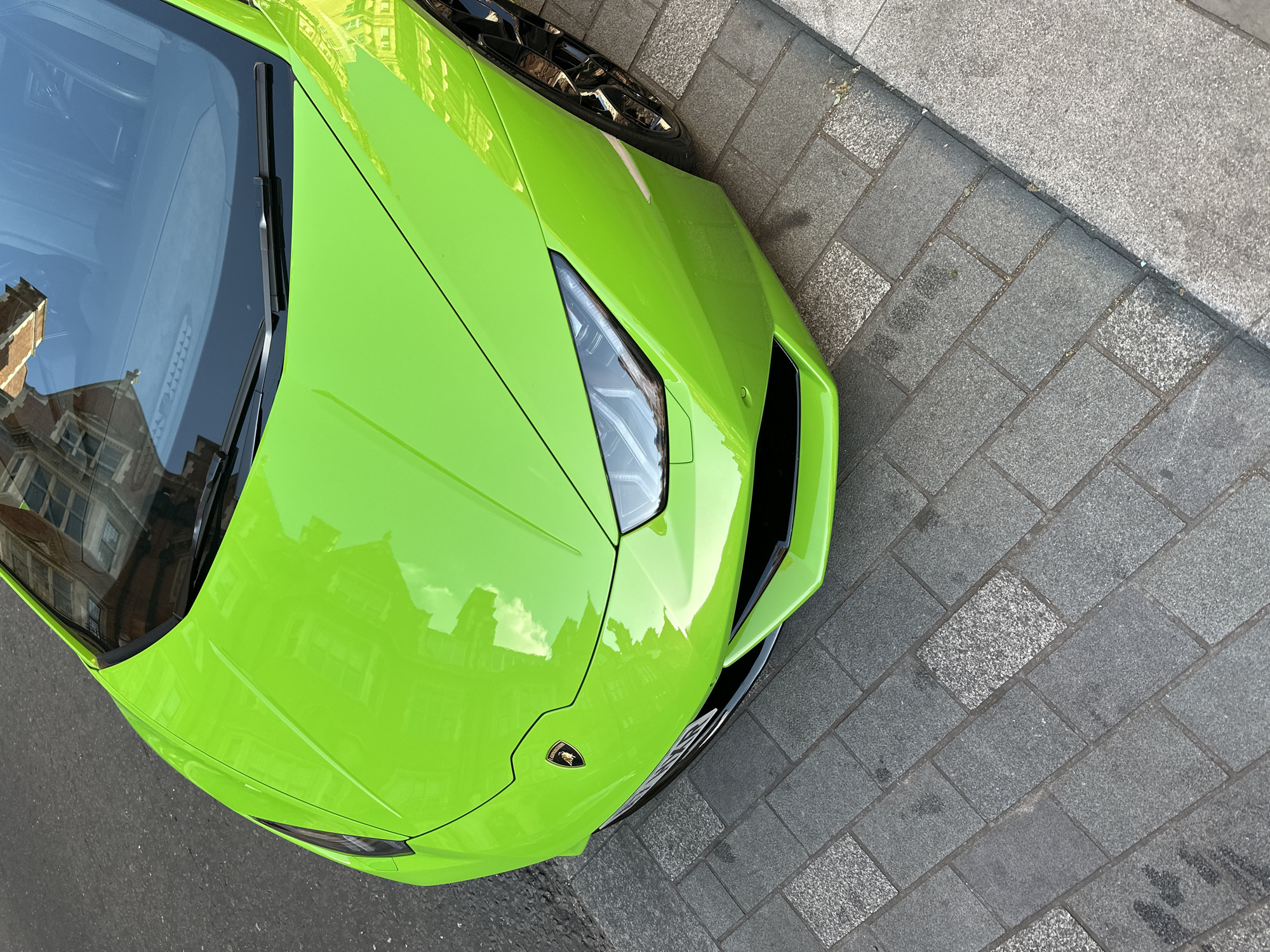 Luxury supercars gather on London cobblestone streets near Hepburn plaque