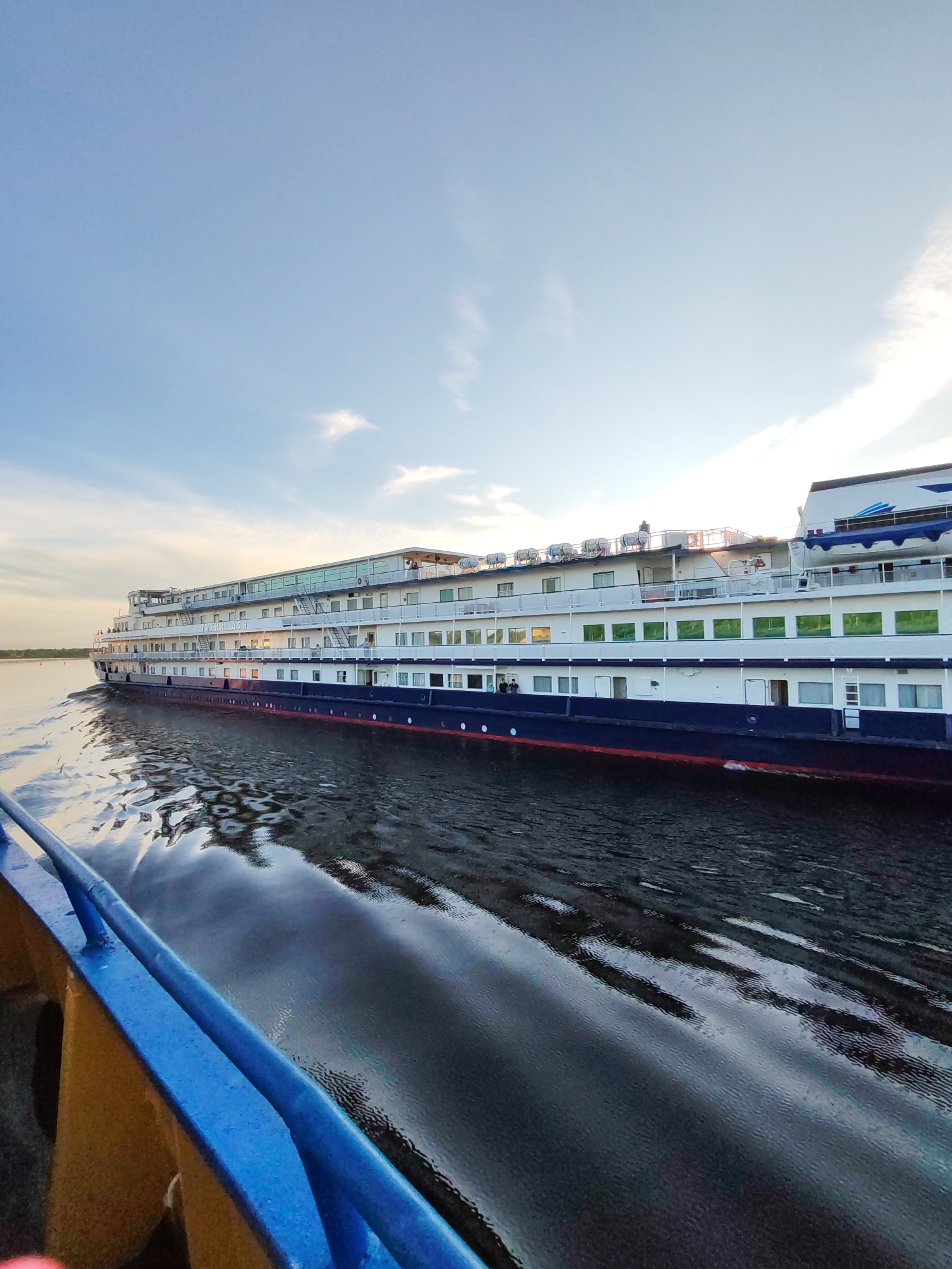 Cruise ship passes under Sheksna river bridge at golden hour