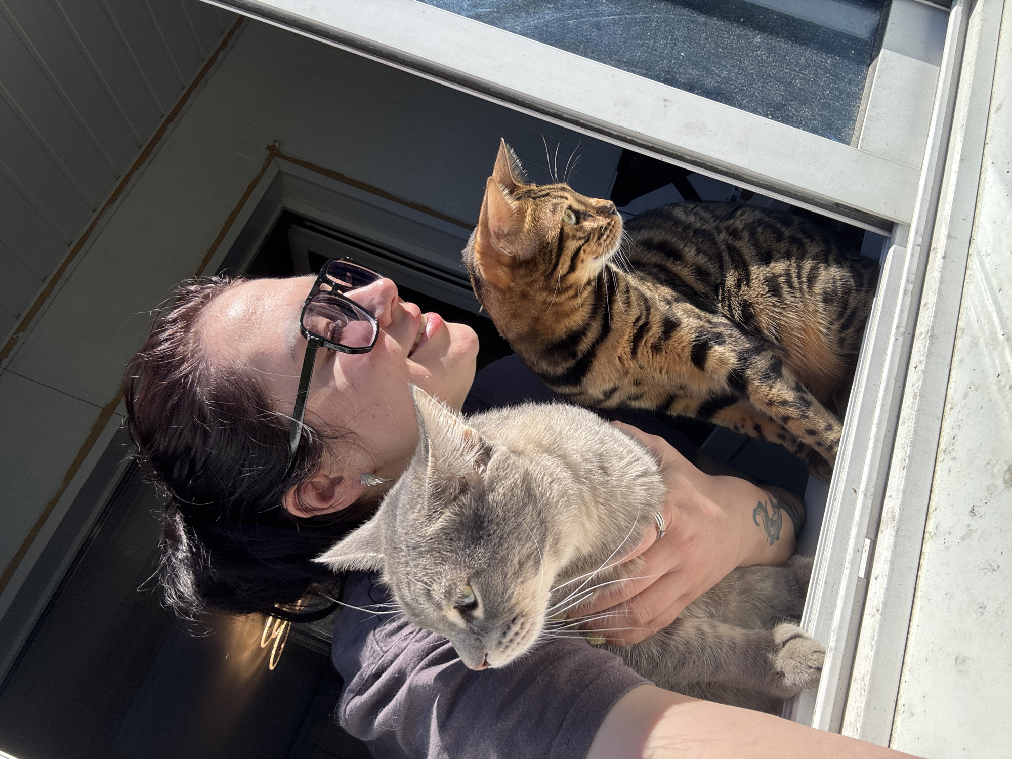 Woman poses with cats while rats rest in cages