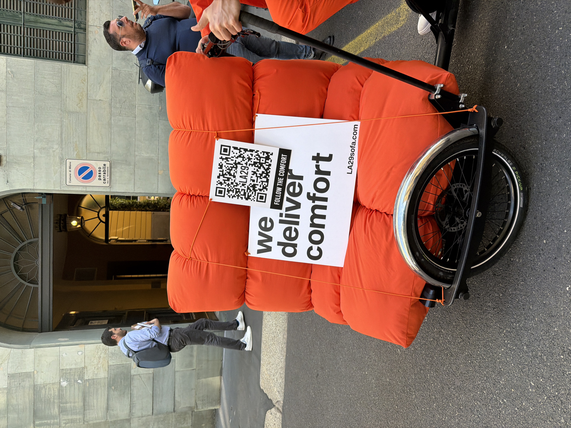 Orange sofa transported through Milan streets in daylight