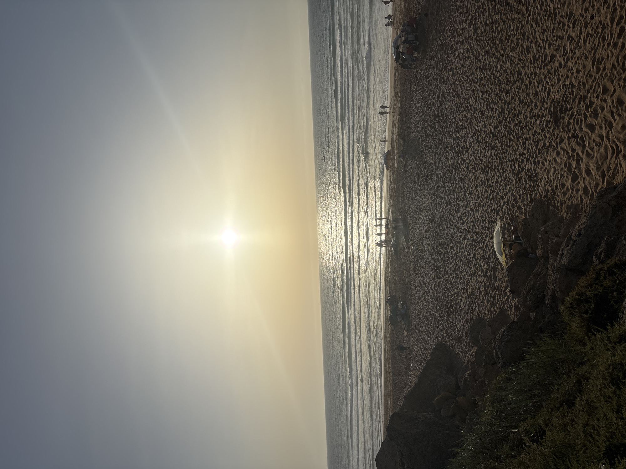 A busy sunny beach day from road to shoreline