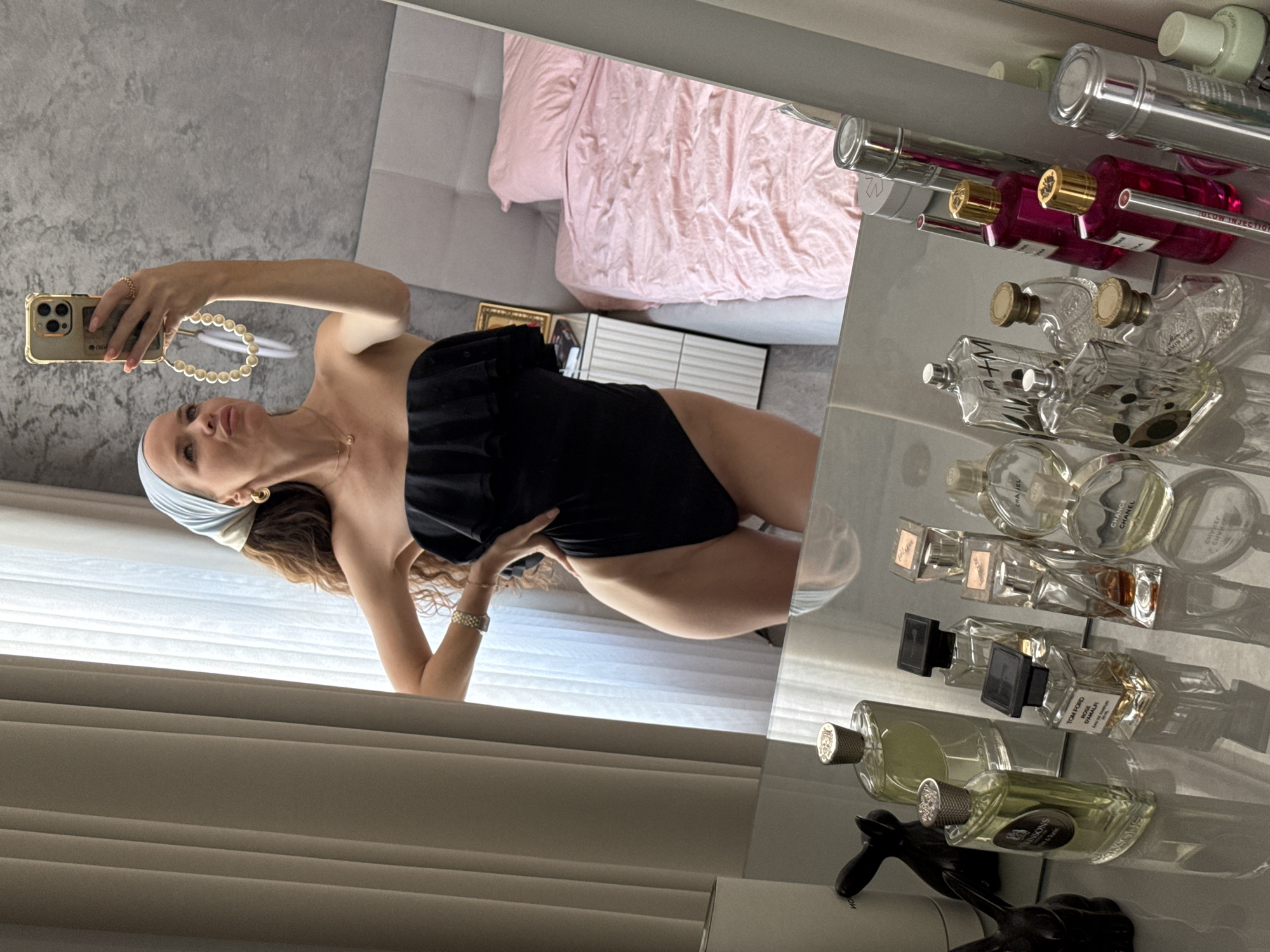 Mirror selfie in a black ruffled swimsuit and pearl necklace