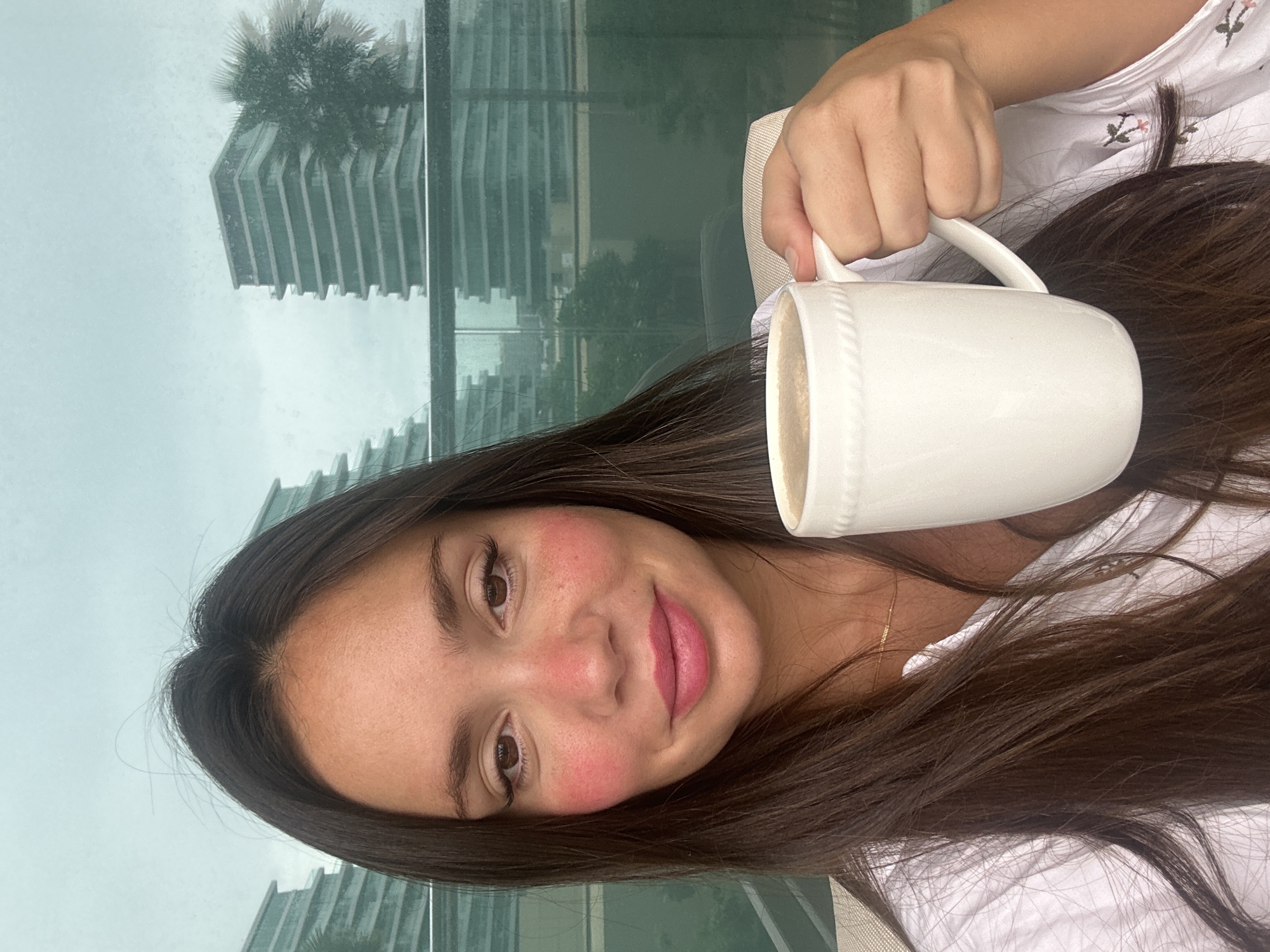 Woman enjoys morning coffee by window in Abu Dhabi