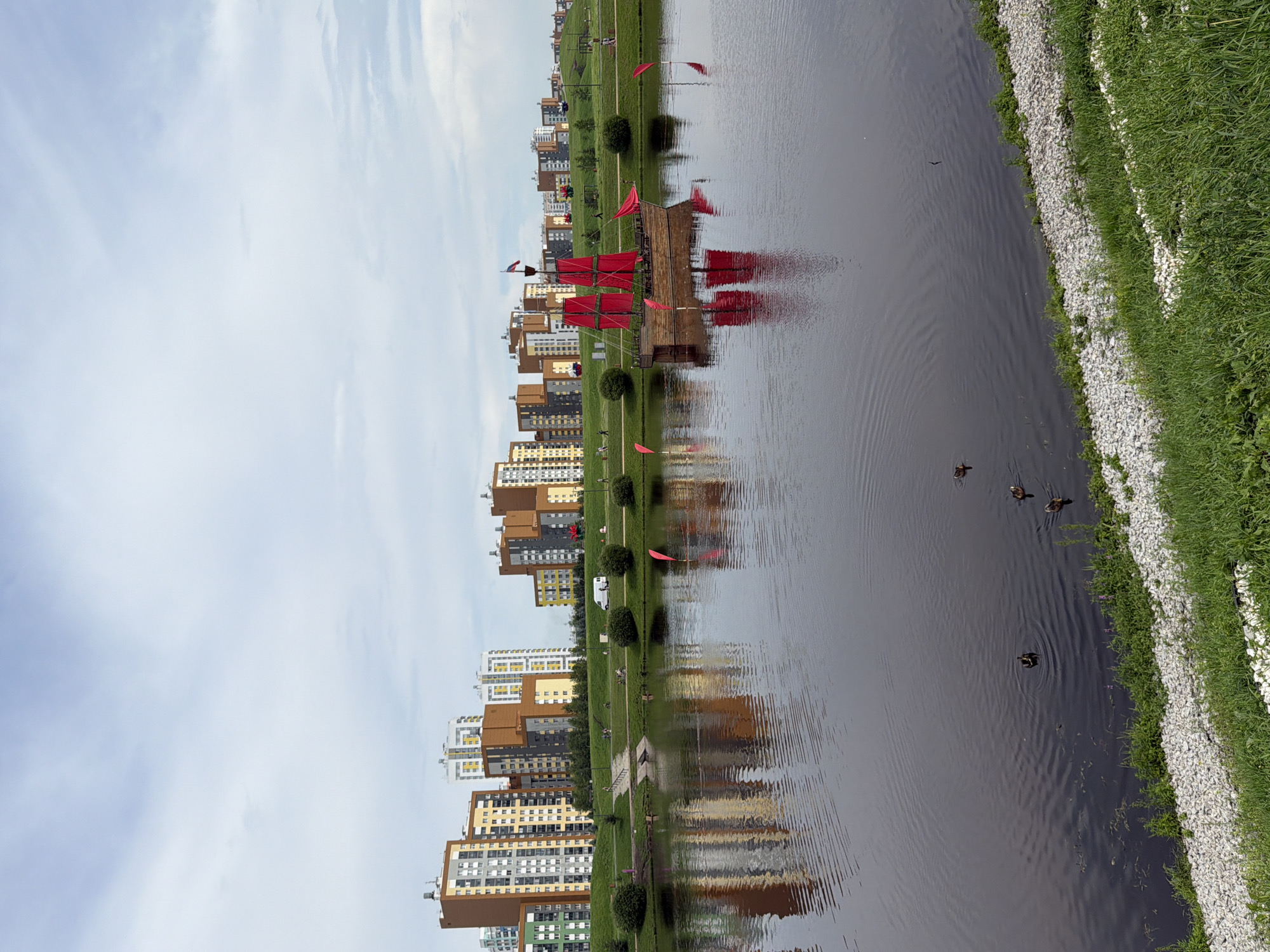 Red-sailed ship and pigeons along a Yekaterinburg waterfront