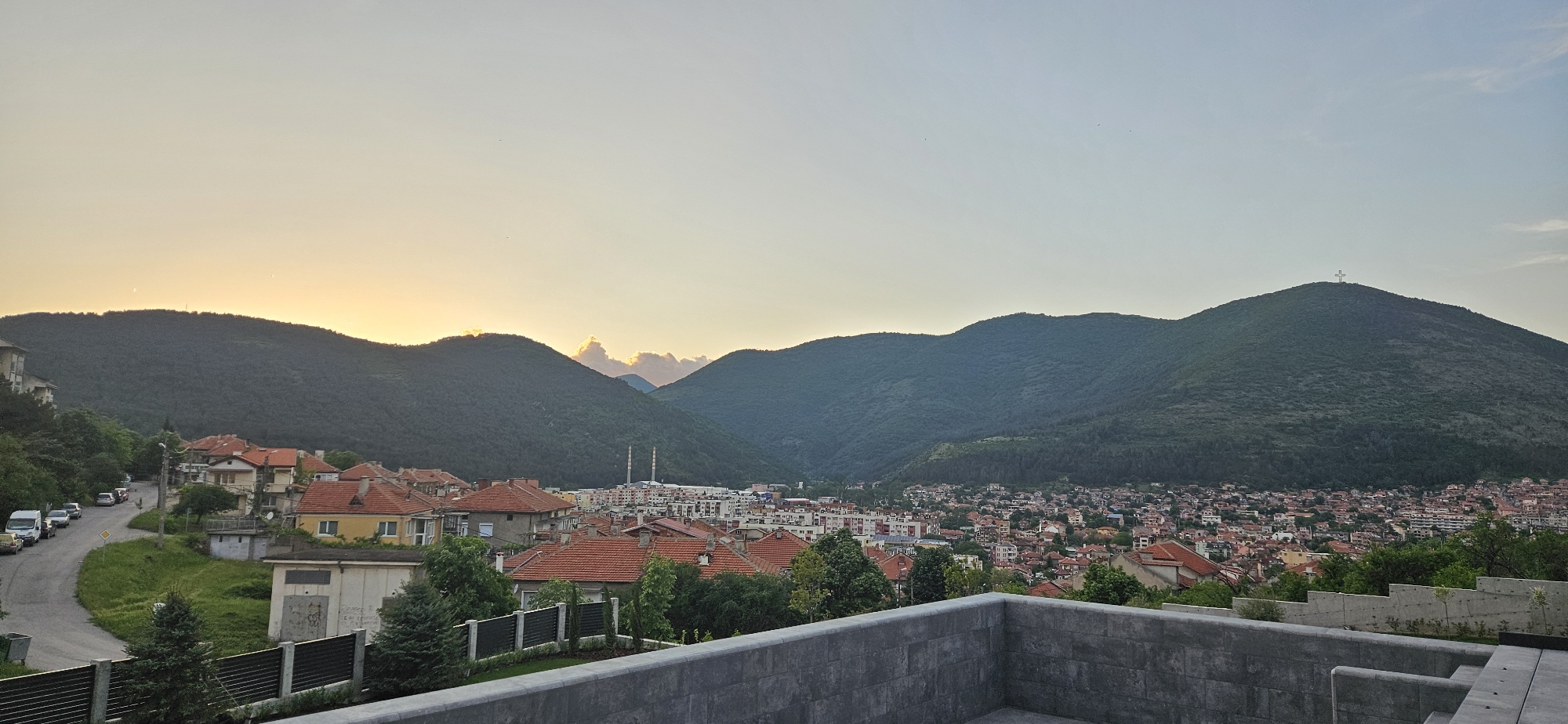 Evening scenes captured across mountainous town with illuminated cross